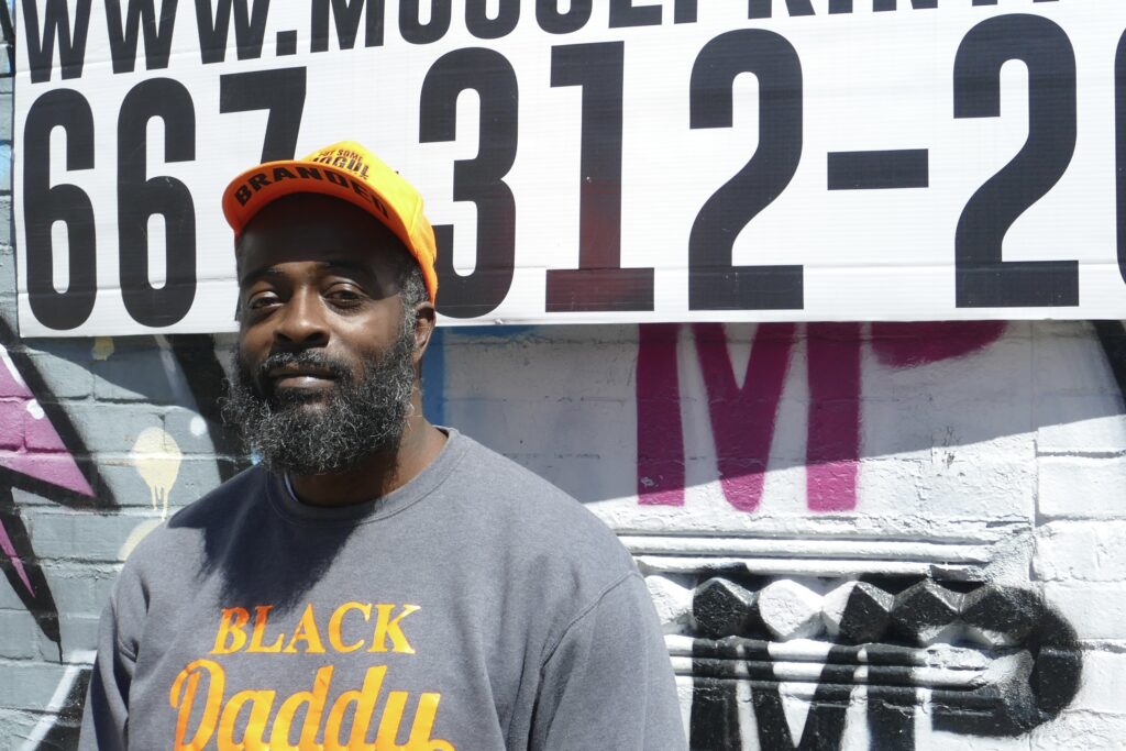 Daryell Mack in front of his store front, sporting a shirt and hat printed by Mogul Printing. (Miles Grovic/Capital News Service)