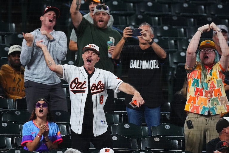 Orioles fans cheer as play resumes after a rain delay in the sixth inning of a baseball game against the Colorado Rockies in Denver.
