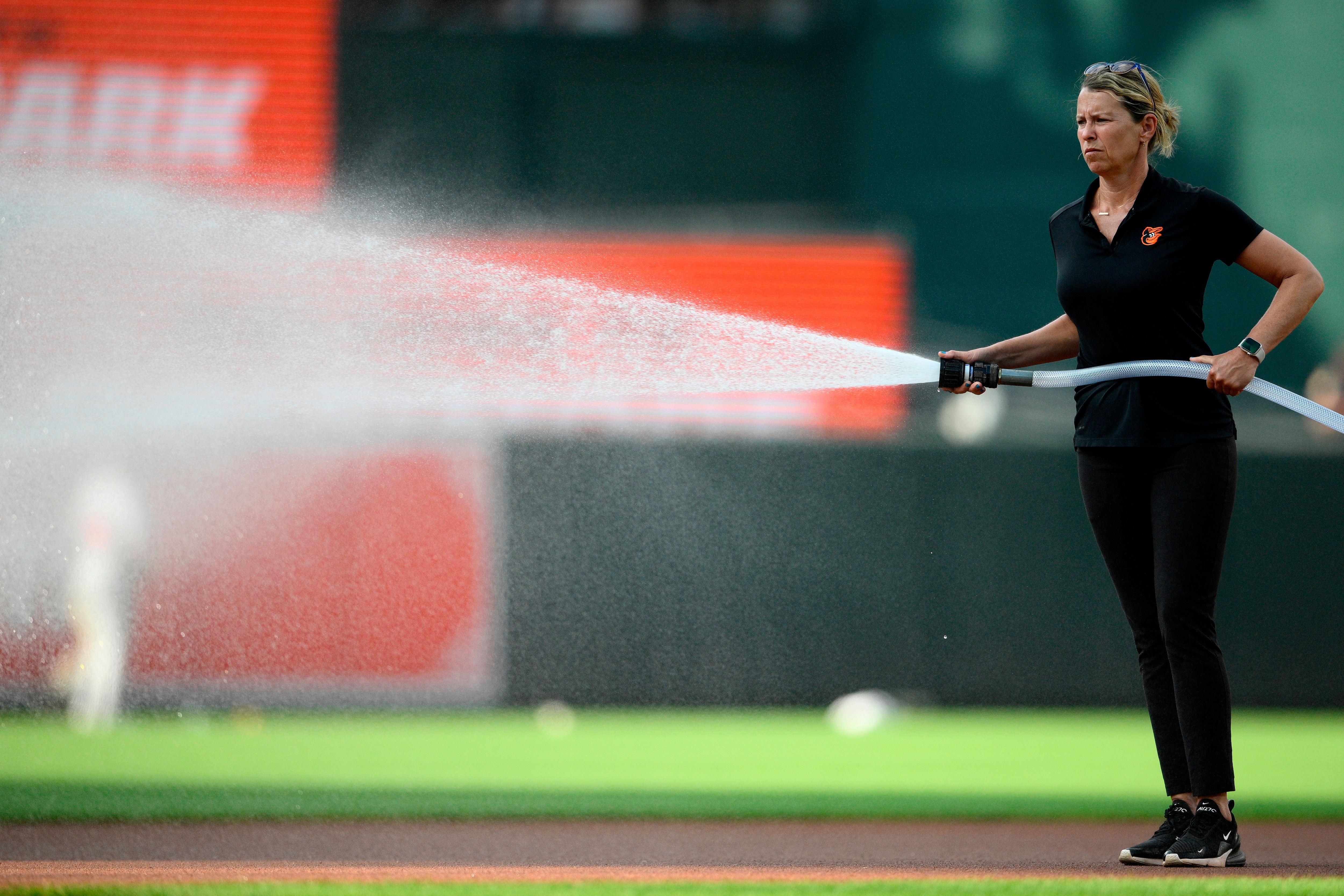 Orioles head groundskeeper Nicole Sherry sprays the field before a baseball game between the Orioles and the Atlanta Braves in 2024.