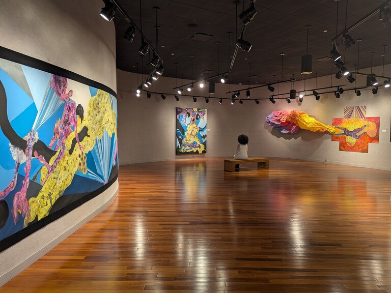 Artist Lusmerlin Lantigua sits among pieces included in her exhibit at Howard County Community College, "Big Bang Baby."