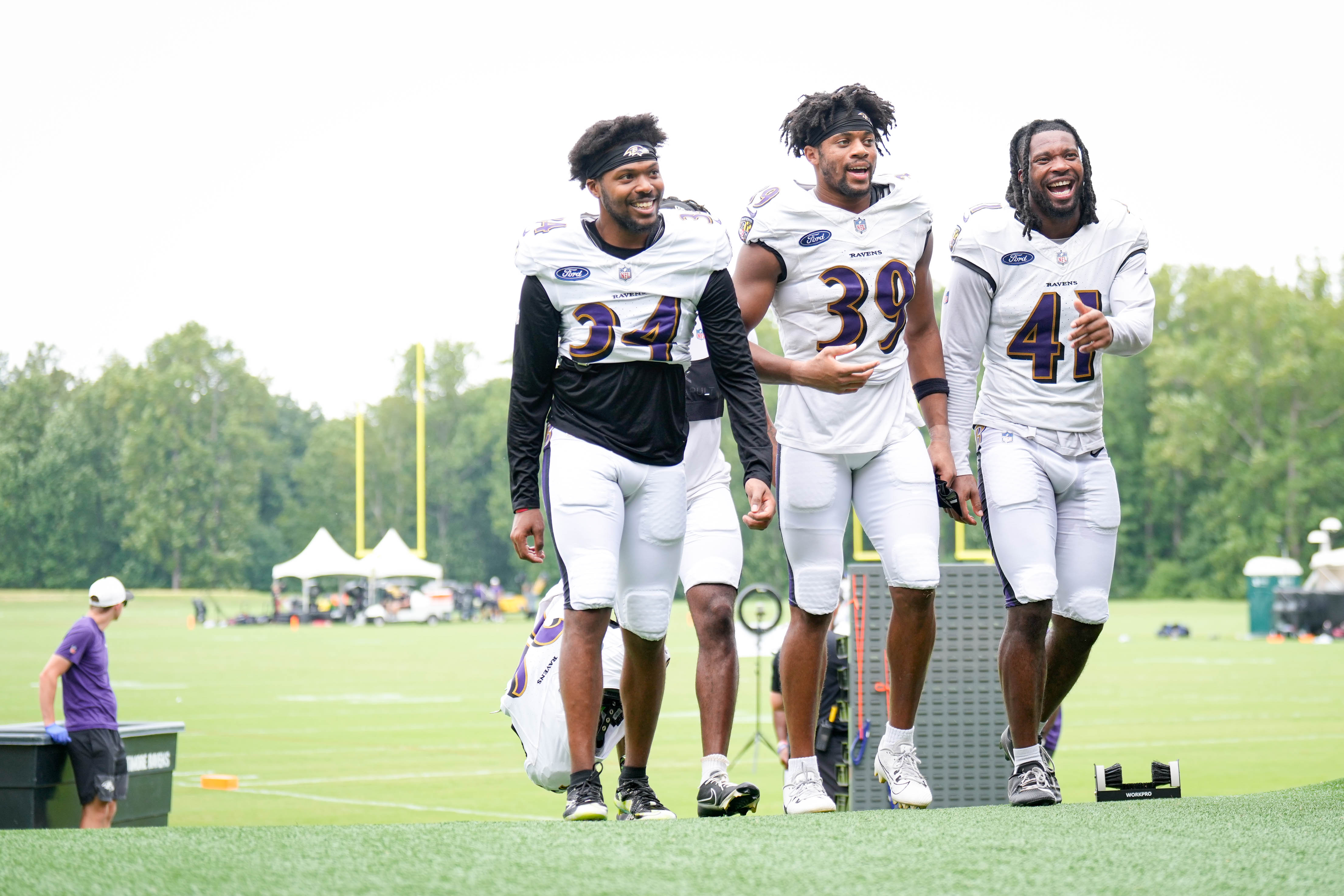 Newly signed Baltimore Ravens defensive end Thomas Graham Jr. (34) jokes with safeties Keondre Jackson (39) and Desmond Igbinosun (41) as they return to the locker room following the team’s training camp at the Under Armour Performance Center in Owings Mills, Md. on Tuesday, August 19, 2025.