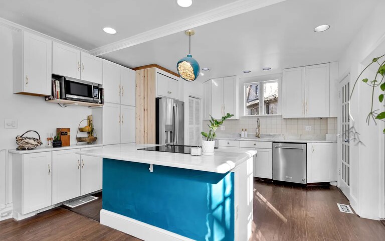 A clean and bright kitchen with white countertops and an island with a bright blue base.