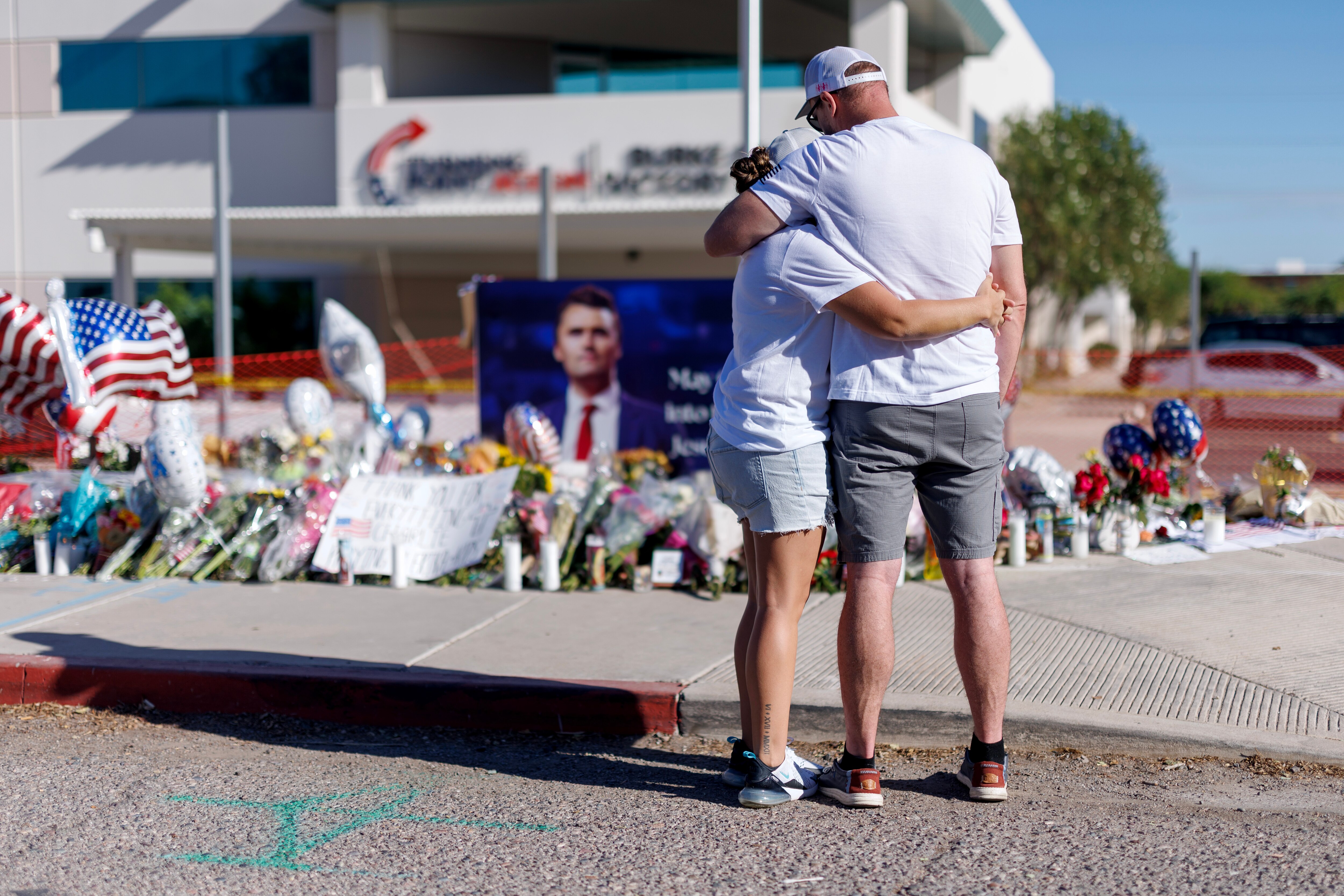 PHOENIX, ARIZONA - SEPTEMBER 12: People embrace in front of a memorial for Charlie Kirk at the Turning Point USA headquarters on September 12, 2025 in Phoenix, Arizona. Kirk, the CEO and co-founder of Turning Point USA, was shot and killed on Wednesday in Utah.
