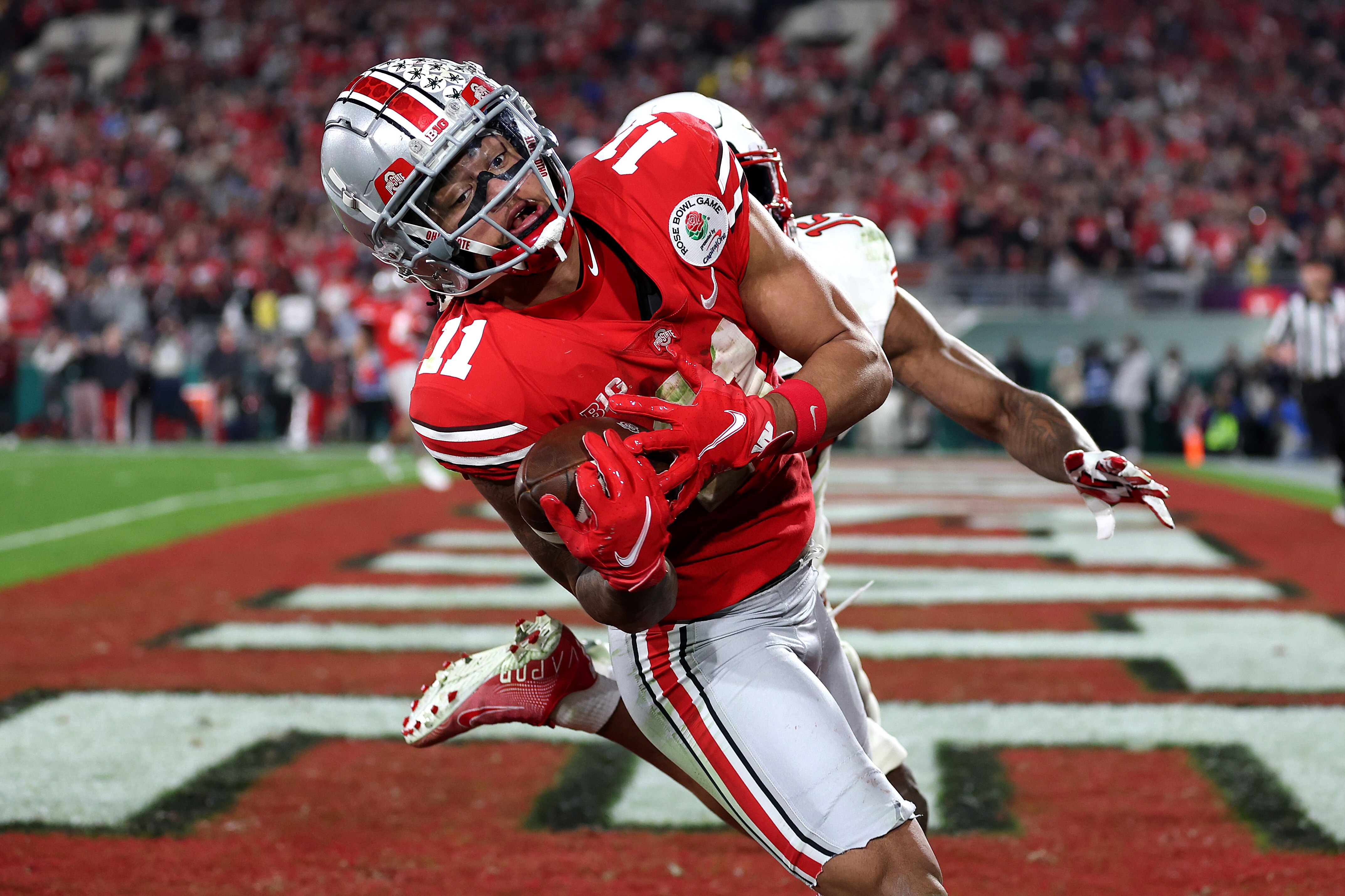 PASADENA, CALIFORNIA - JANUARY 01: Jaxon Smith-Njigba #11 of the Ohio State Buckeyes catches a touchdown pass as Malone Mataele #15 of the Utah Utes defends during the fourth quarter in the Rose Bowl Game at Rose Bowl Stadium on January 01, 2022 in Pasadena, California.