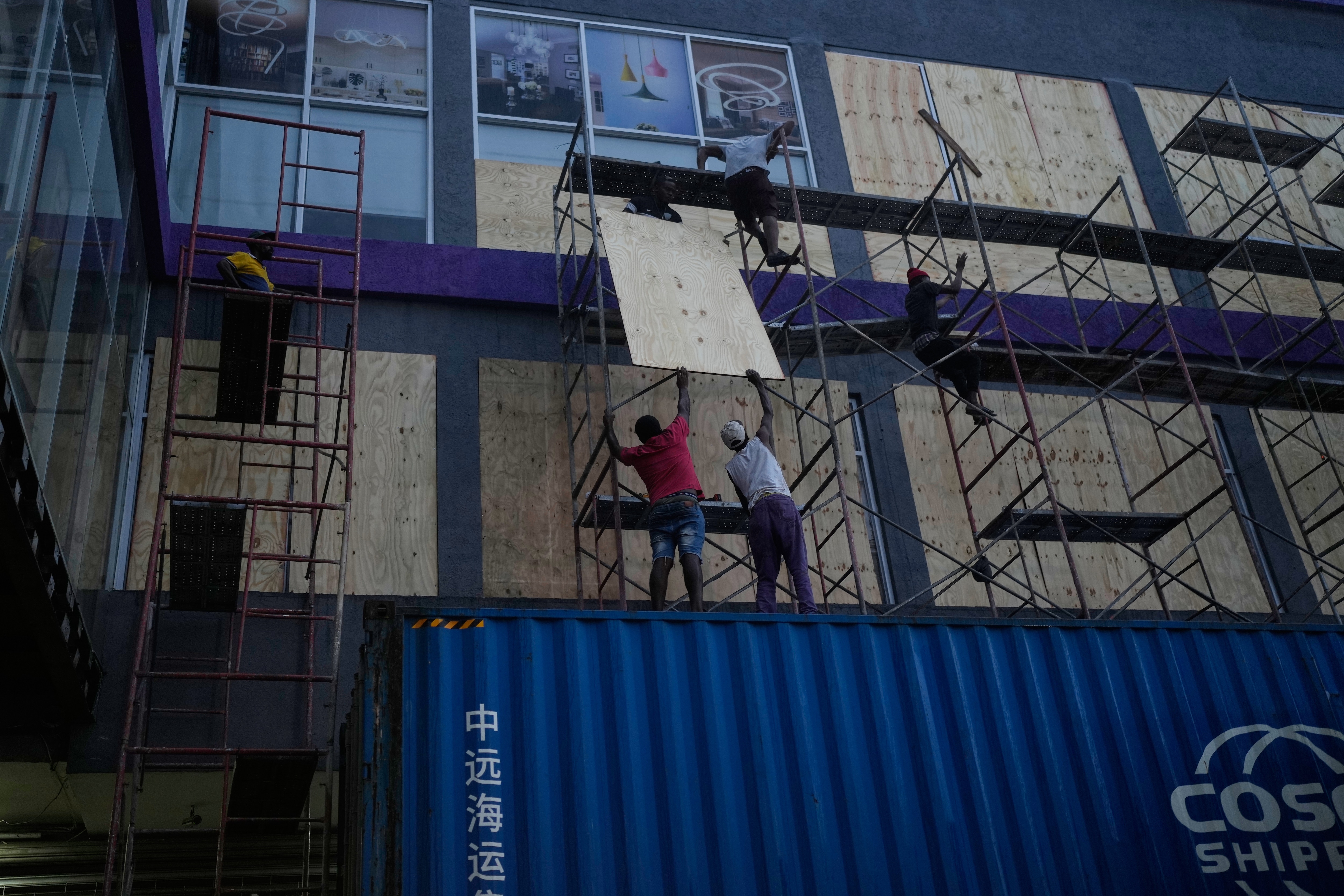 Workers board up shop windows ahead of Hurricane Melissa's forecast arrival in Kingston, Jamaica, Sunday, Oct. 26, 2025. (AP Photo/Matias Delacroix)