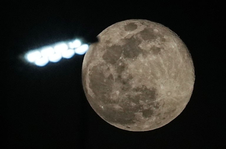 The supermoon rises above a street lamp outside Phnom Penh Cambodia, Friday, Dec. 5, 2025