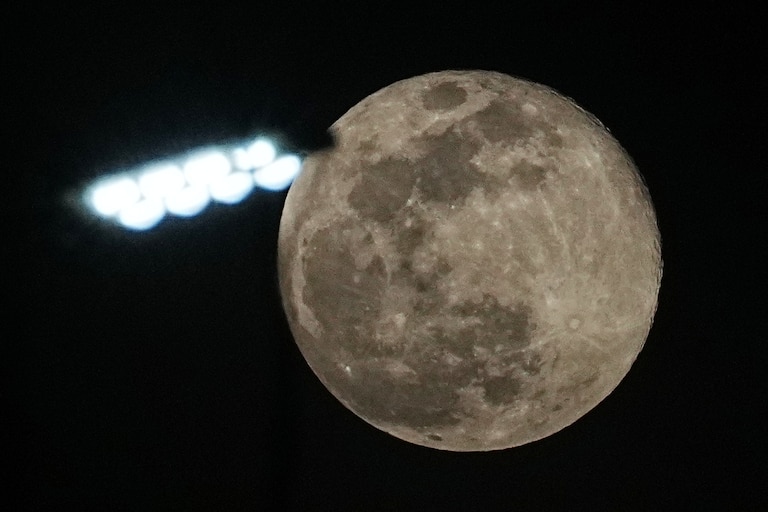 The supermoon rises above a street lamp outside Phnom Penh Cambodia, Friday, Dec. 5, 2025