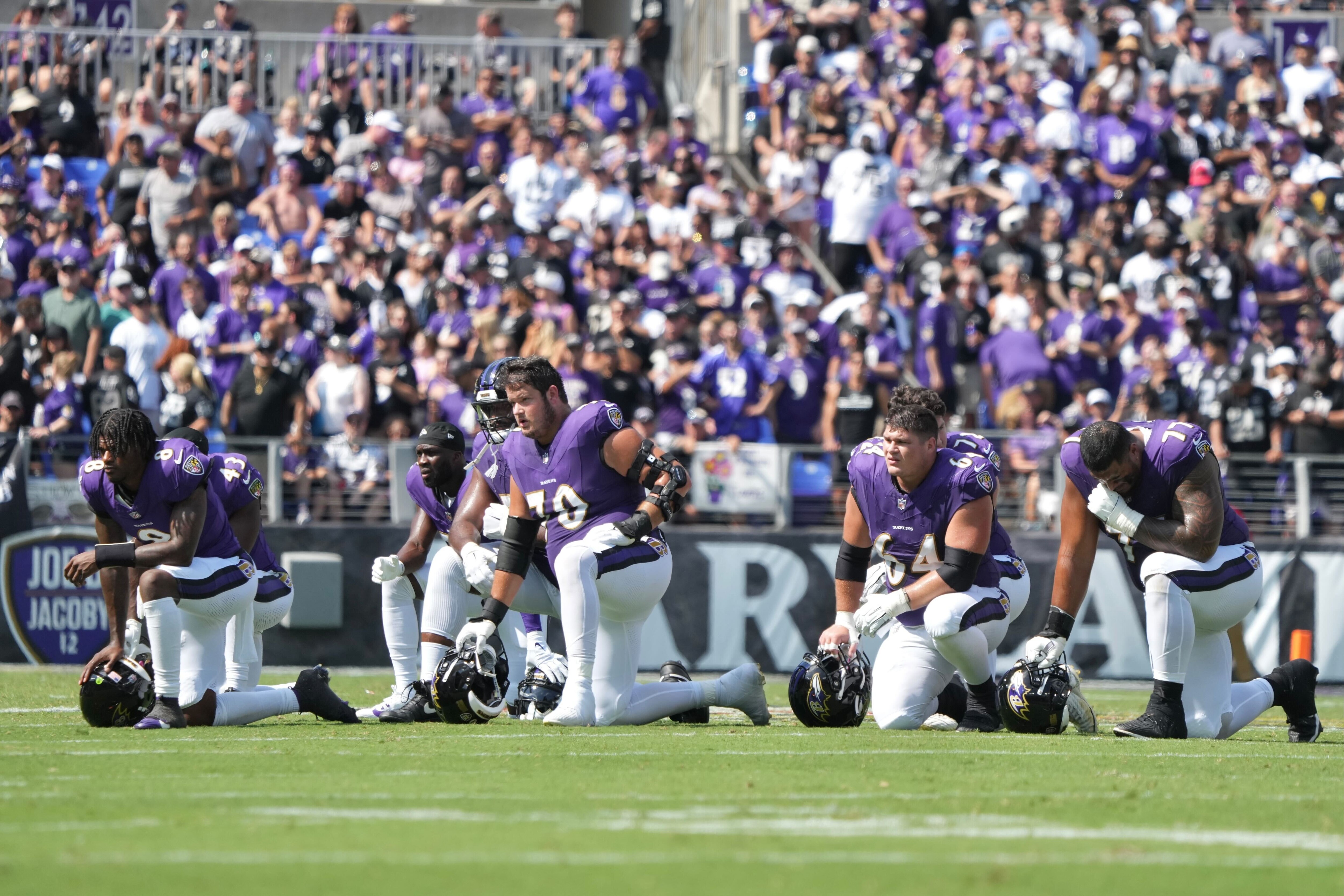 Members of the Baltimore Ravens take a knee on the field during a medical emergency on the sideline.