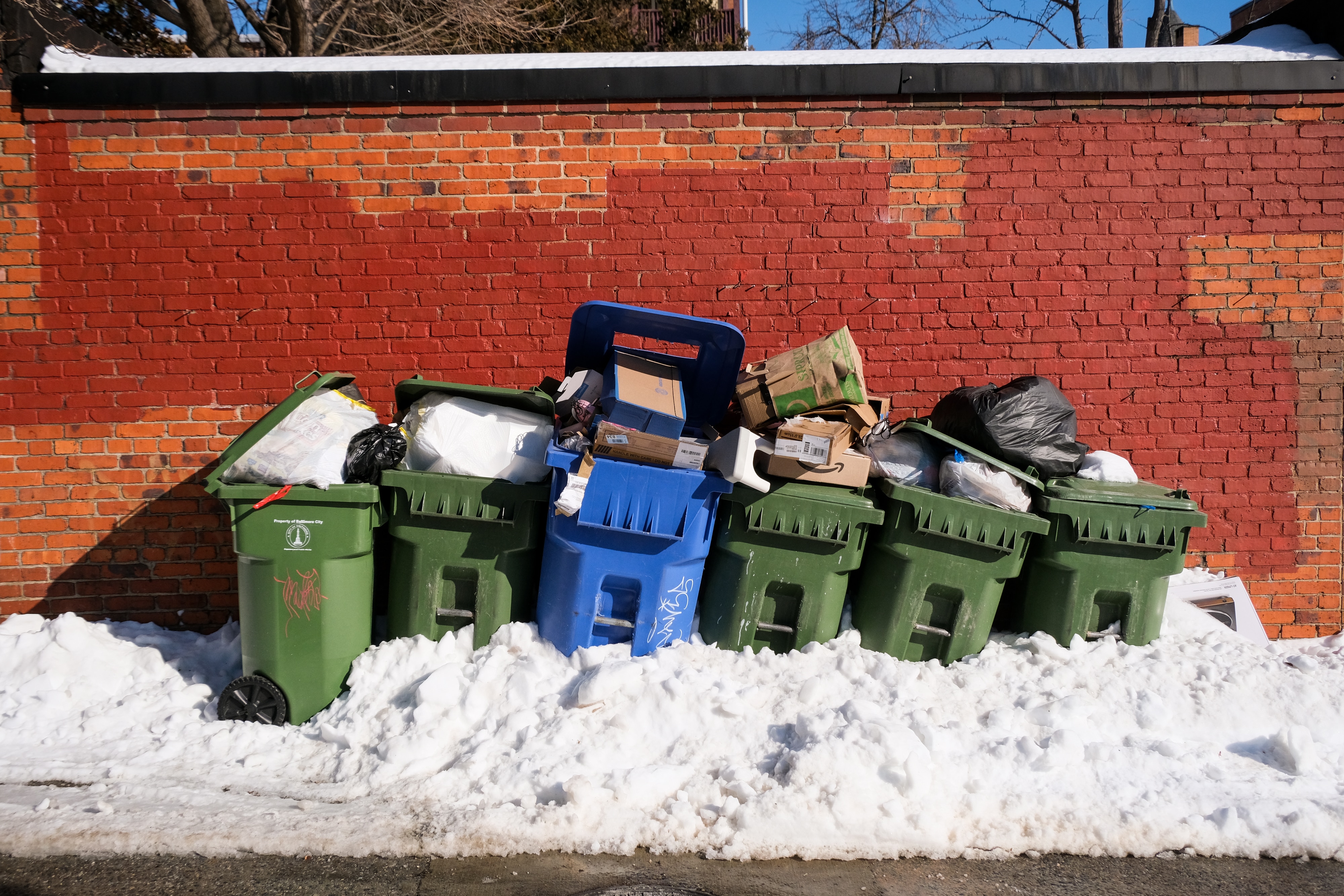 Full garbage and recycling cans buried in snow in the Charles Village neighborhood of Baltimore on Thursday.
