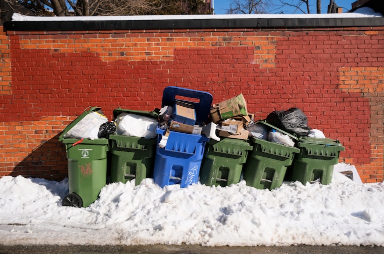 Full garbage and recycling cans buried in snow in the Charles Village neighborhood of Baltimore on Thursday.