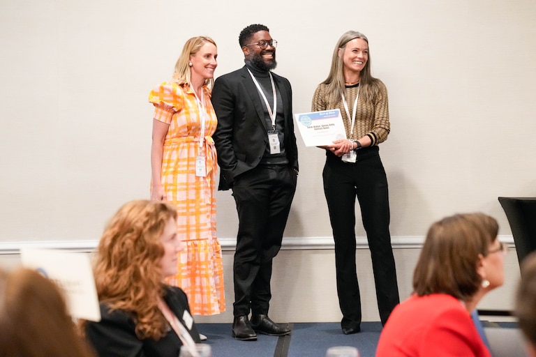 Banner Chief Philanthropy Officer Sarah Walton, left, and graphic designer Glenford Nuñez pose for a photo with MDDC Press president Dawn Gessel as they're presented with a Best of Show award