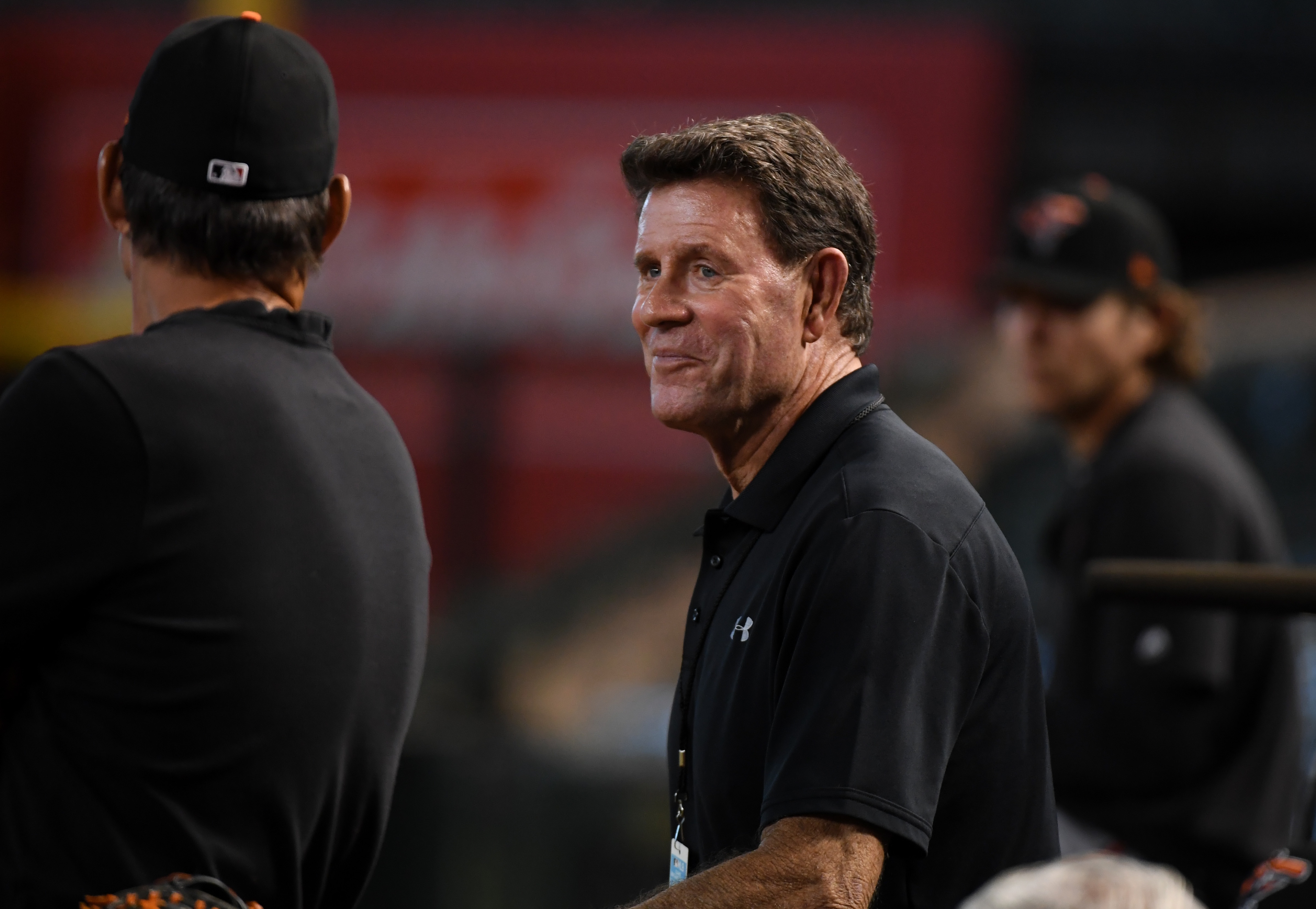 Lead analyst for MASN, Hall of Famer and former pitcher for the Baltimore Orioles Jim Palmer talks with Orioles players in the dugout during batting practice prior to a game against the Arizona Diamondbacks at Chase Field on July 23, 2019 in Phoenix, Arizona.