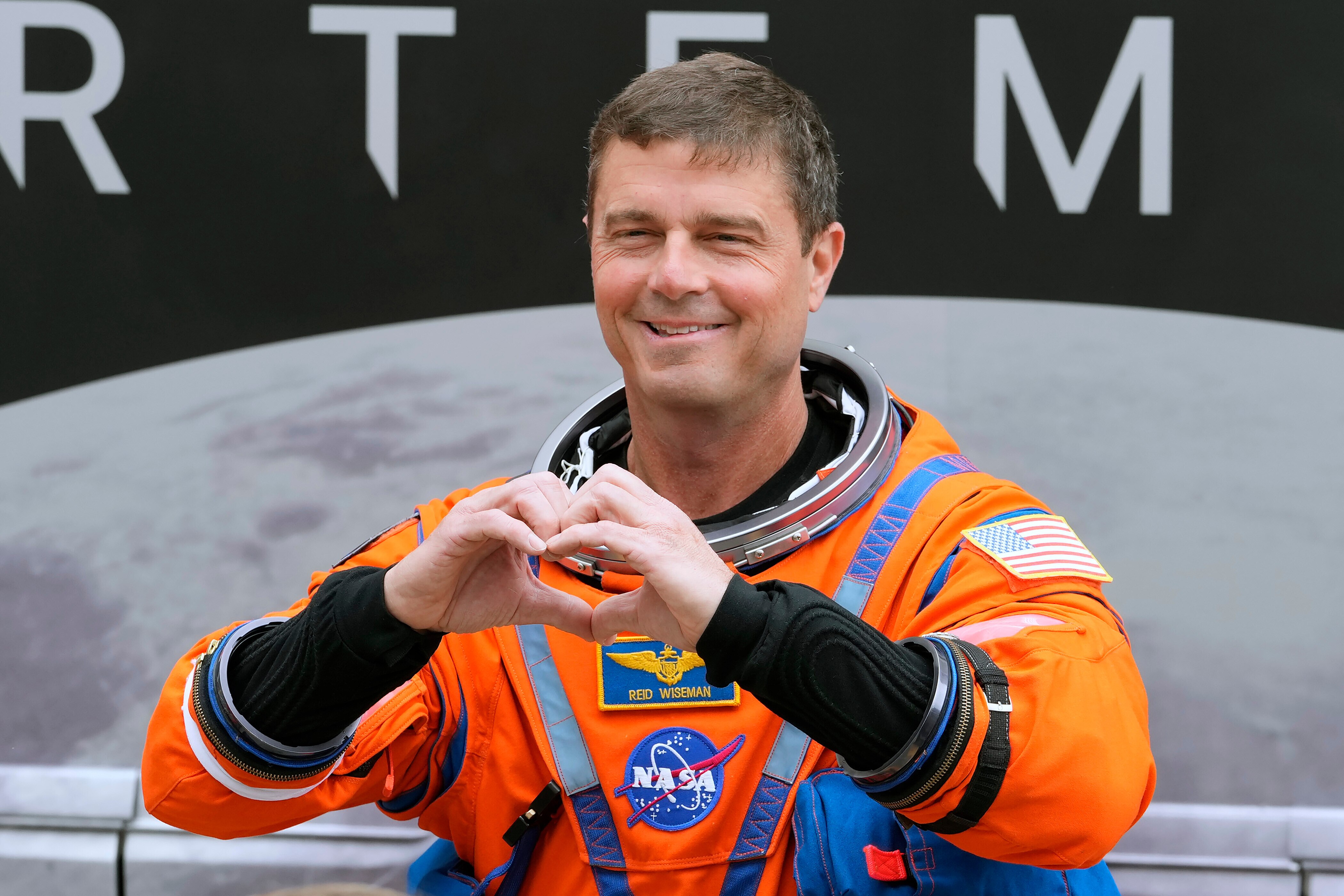 Mission Commander Reid Wiseman makes a heart with his hands as he leaves the Operations and Checkout Building for a trip to Launch Pad 39-B and a planned liftoff on NASA's Artermis II moon rocket at the Kennedy Space Center Wednesday, April 1, 2026, in Cape Canaveral, Fla. (AP Photo/Chris O'Meara)