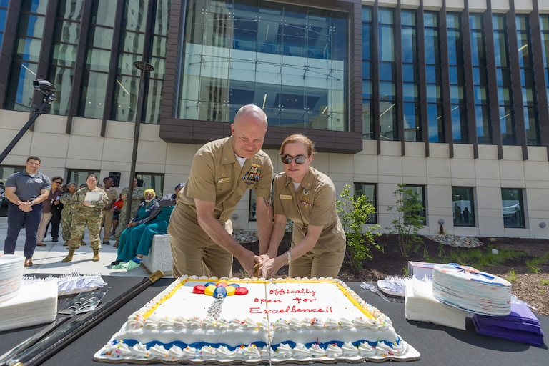 Navy Capt. Melissa Austin, director of the Walter Reed National Military Medical Center, cuts a cake during opening ceremonies for the new Roosevelt Pavilion in June with Capt. Jeffrey Klinger,