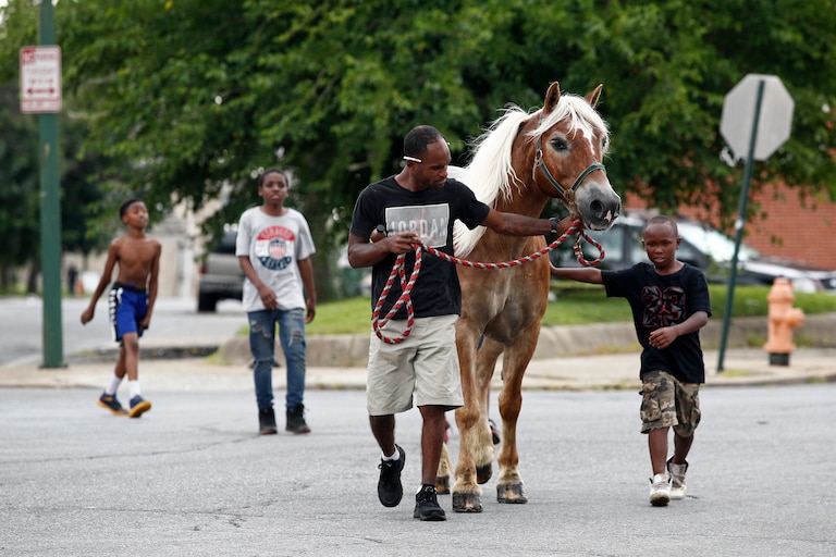 In this June 20, 2018 photo, Bilal Yusuf Abdullah, center, leads a horse to an arabber stable as neighborhood boys tag along in Baltimore. Baltimore has long been the last U.S. city to have functional horse-cart vending.