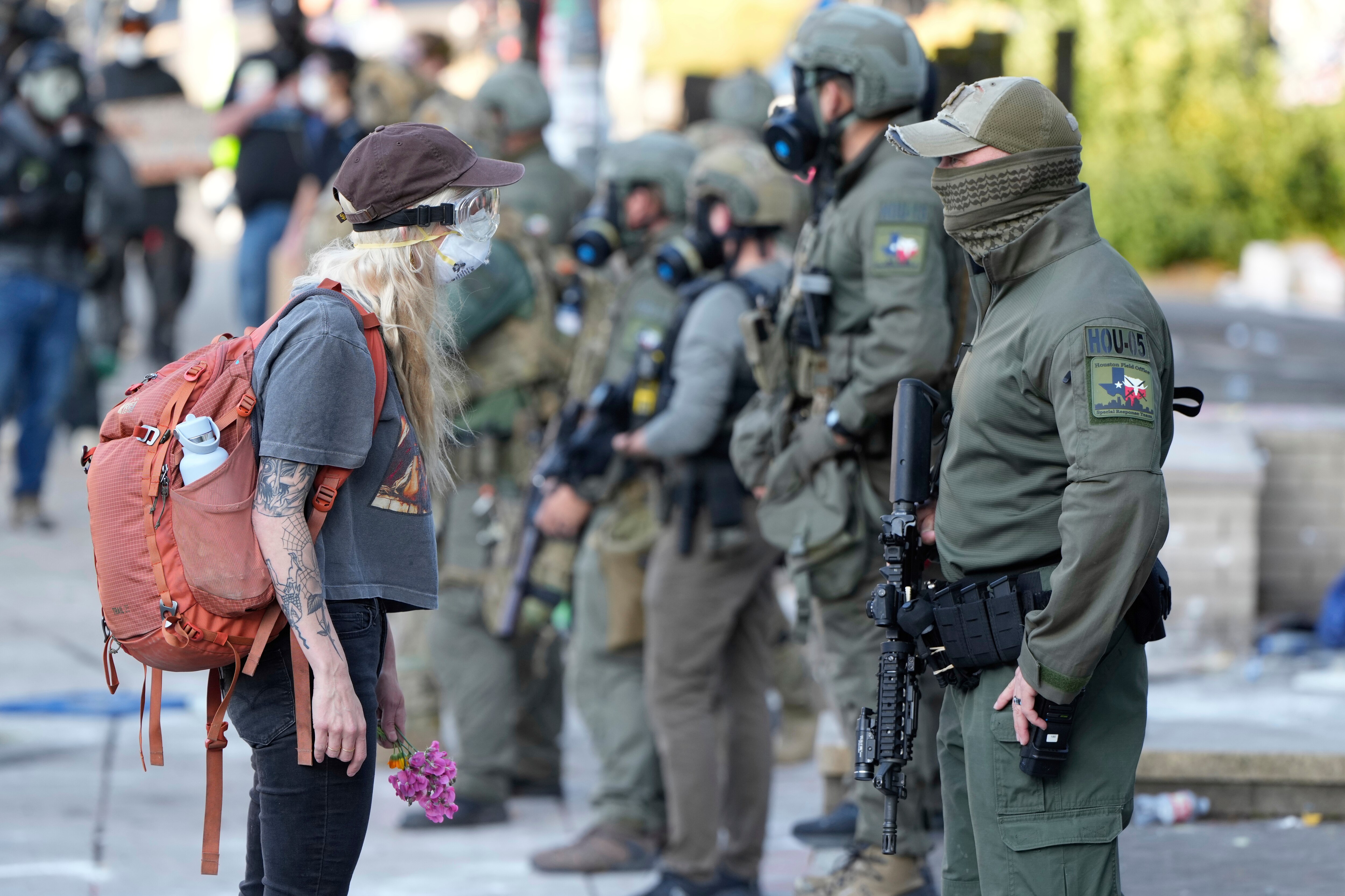 FILE - A woman stands off with a law enforcement officer wearing a Houston Field Office Special Response Team patch outside the U.S. Immigration and Customs (ICE) building during a protest Saturday, June 14, 2025, in Portland, Ore. (AP Photo/Jenny Kane, File)