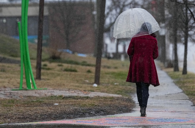 A woman with an umbrella walks past Garrett Park on E. Patapsco Ave. on a rainy day in Brooklyn, Md. on Wednesday, March 5, 2025.