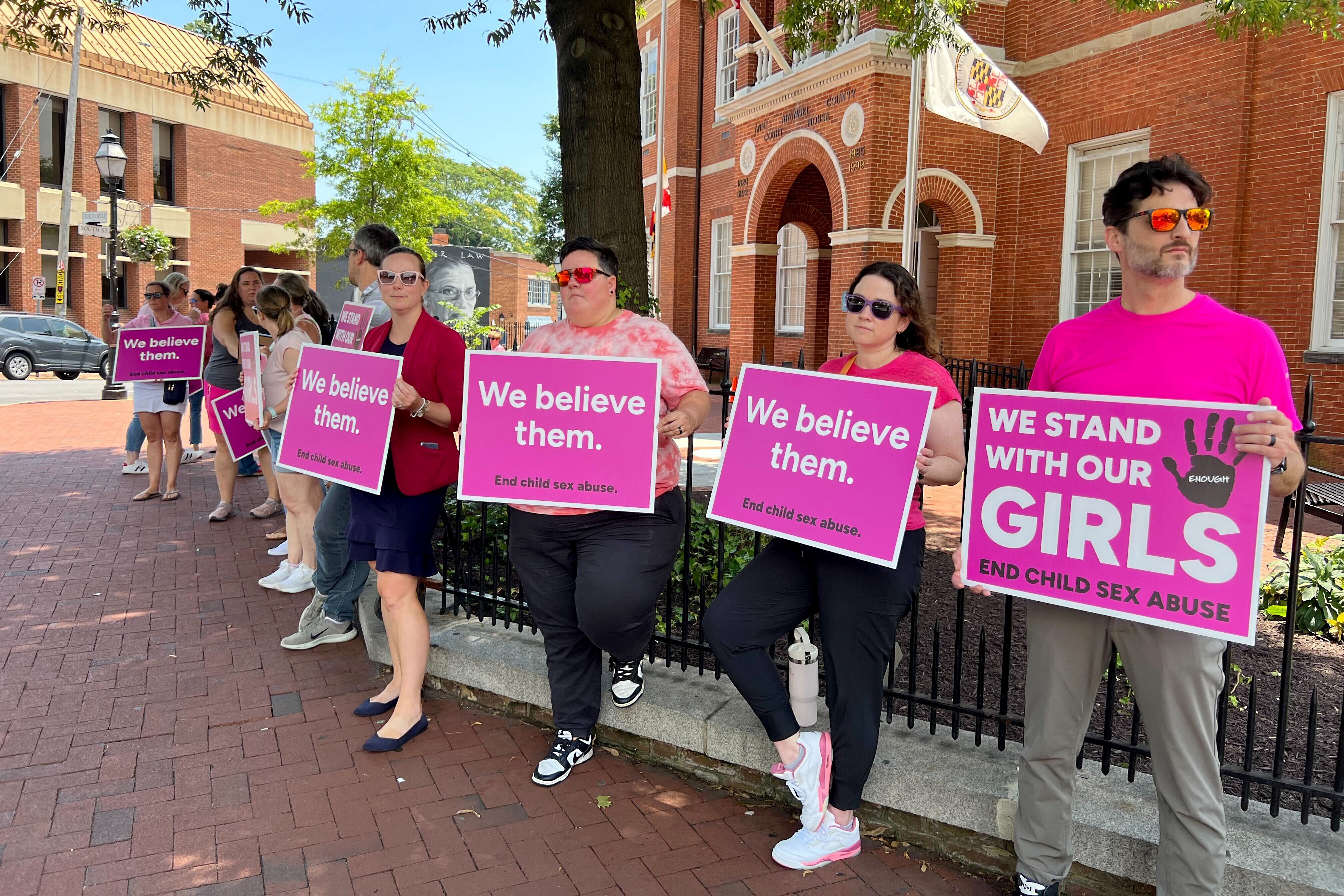 Protesters stand holding signs outside of the Anne Arundel County Courthouse on Wednesday, June 18, 2025, ahead of the bail hearing for Matthew Schlegel.