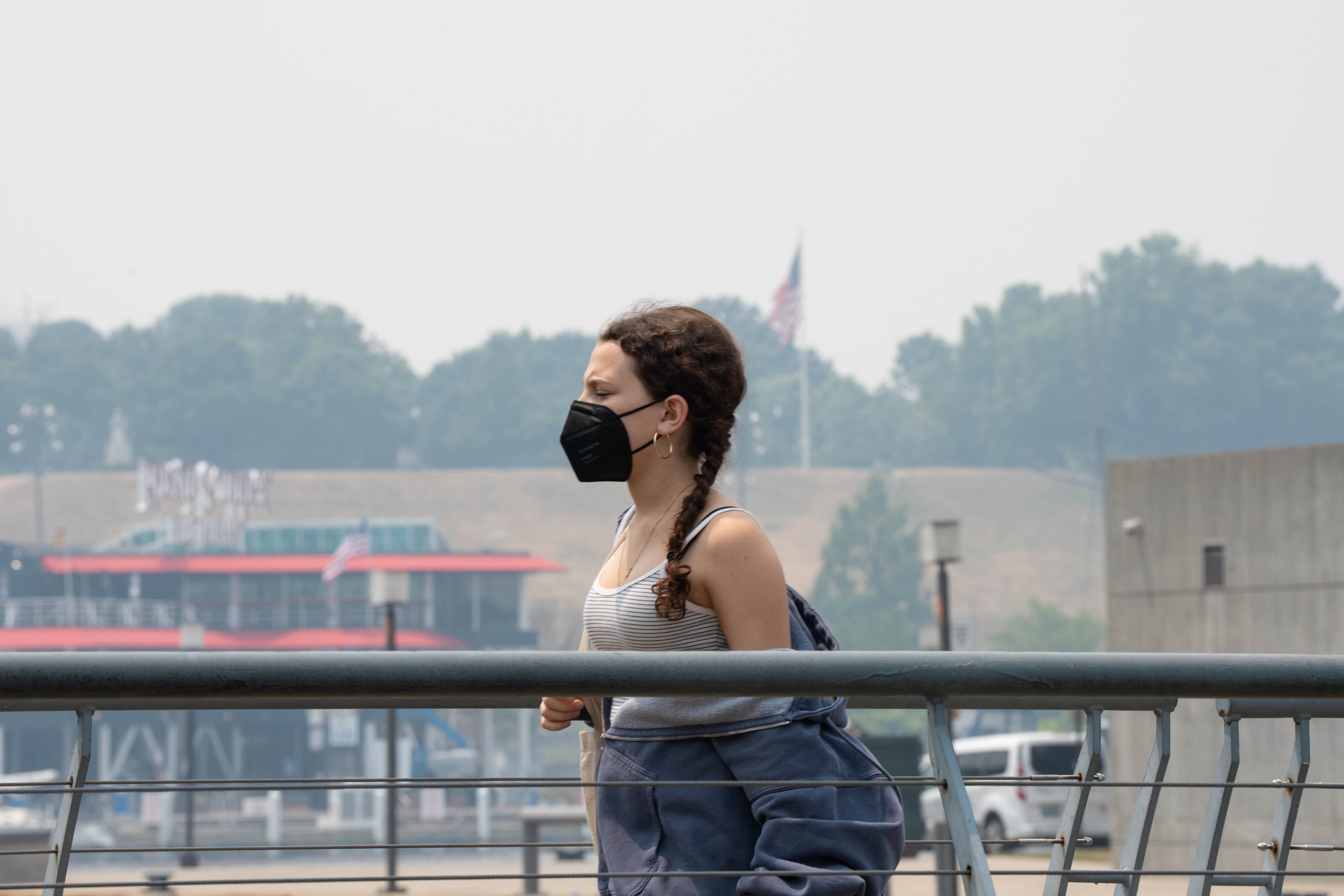 A woman walks in the Inner Harbor as Baltimore is blanketed in dangerous levels of smoke from Canadian wildfires on Thursday, June 8, 2023.