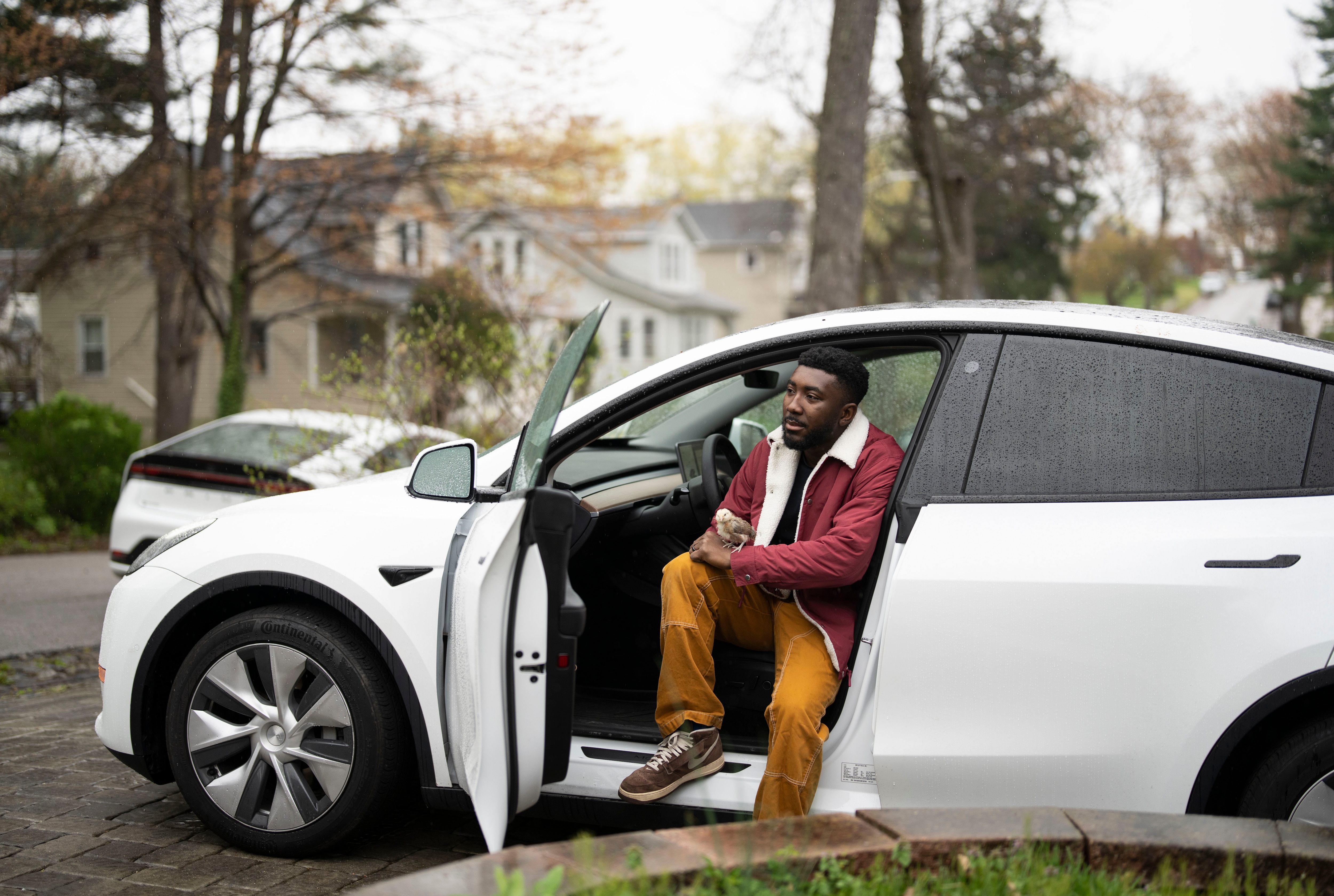 Cadeem Franklin holds his chicken while sitting inside of his Tesla outside of his home in Baltimore, Friday, April 11, 2025.
