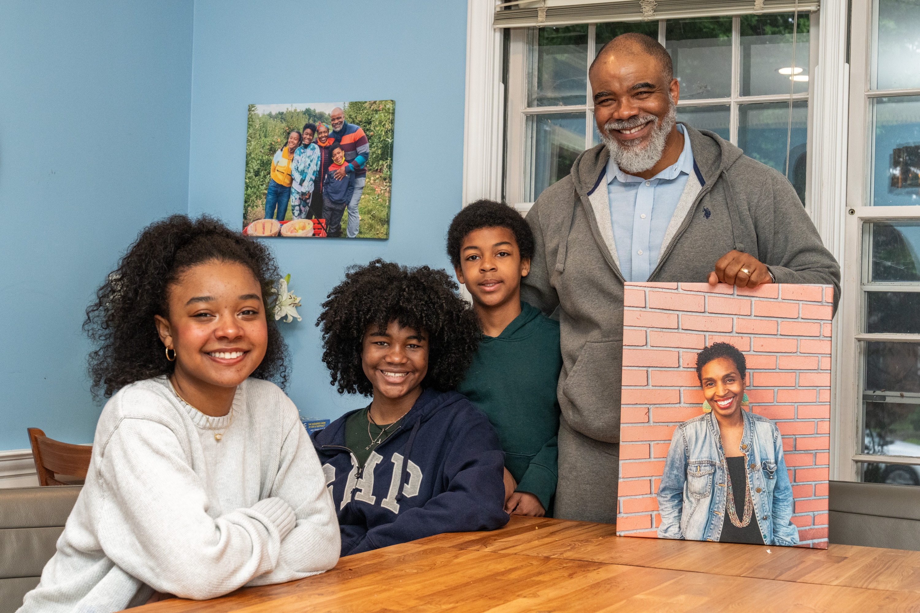 From left, London, Clarke and Elijah and their father, Nathan Connolly, pose with a photo of Shani Mott.