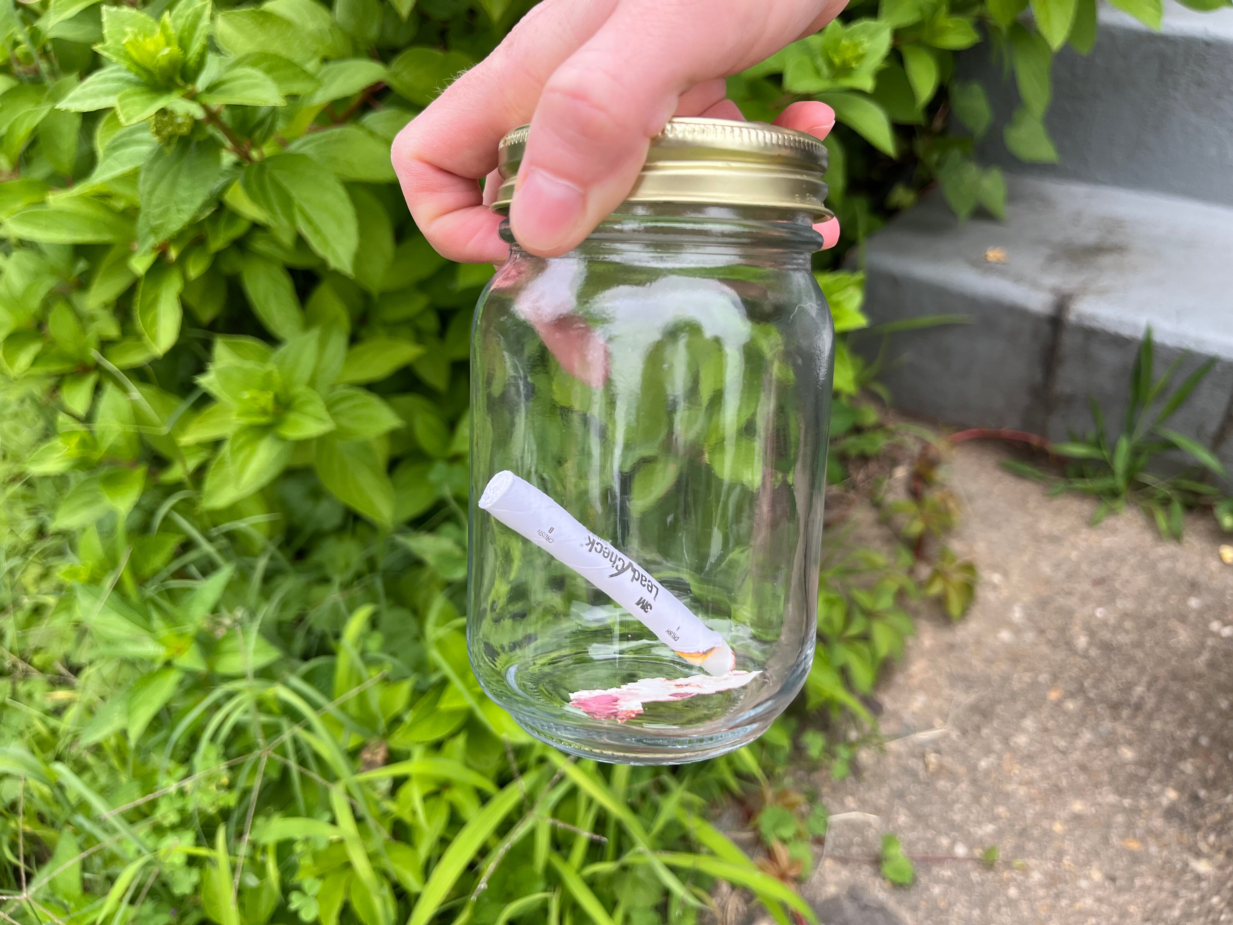 Carol Jarvis holds a jar with piece of red paint. She has been collecting them to test for lead.