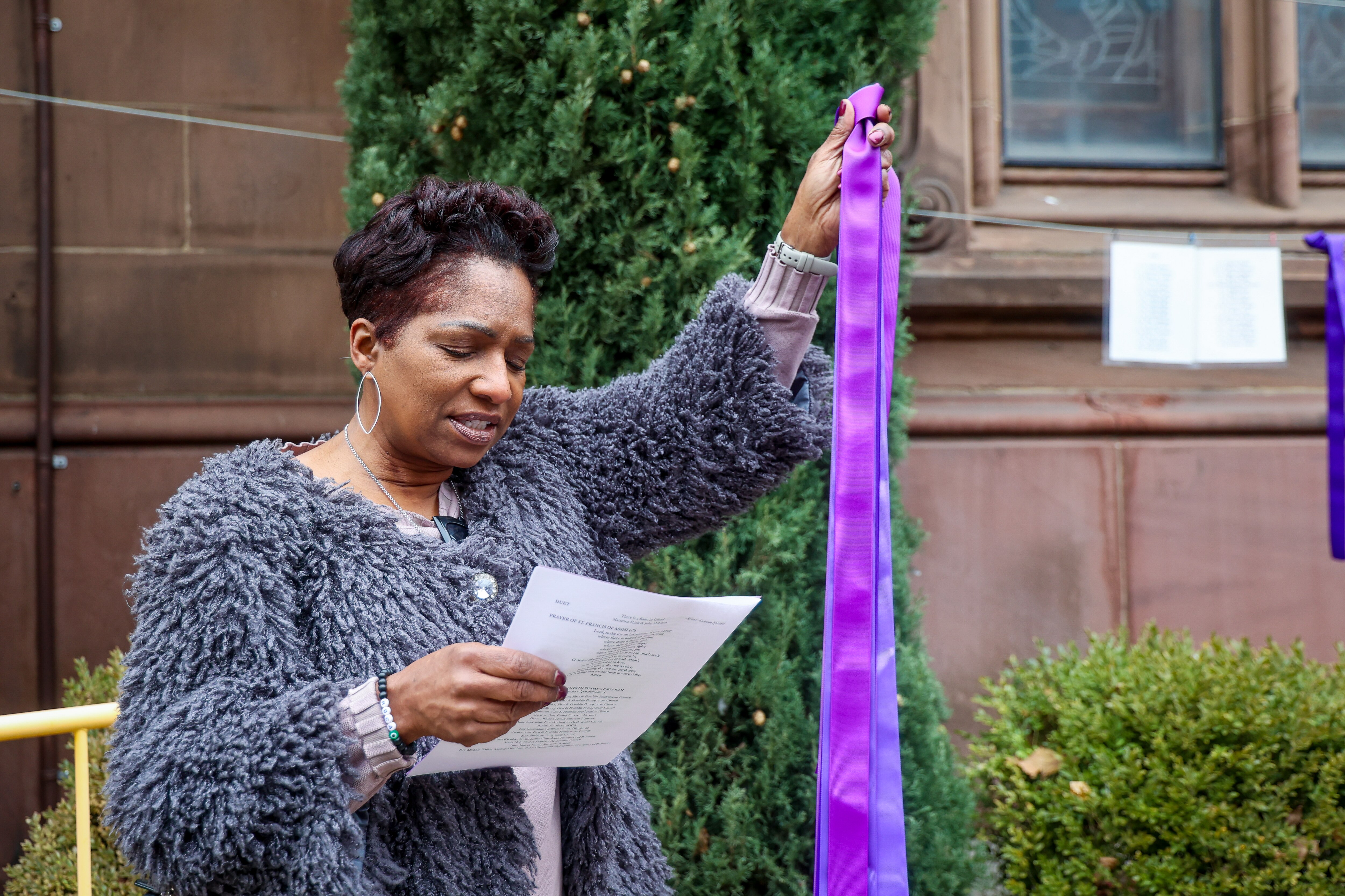 Sunday February 2, 2025 — Andrea Harrison holds up a purple ribbon at First and Franklin Presbyterian Church as part of an event to honor the city's homicide victims in 2024.