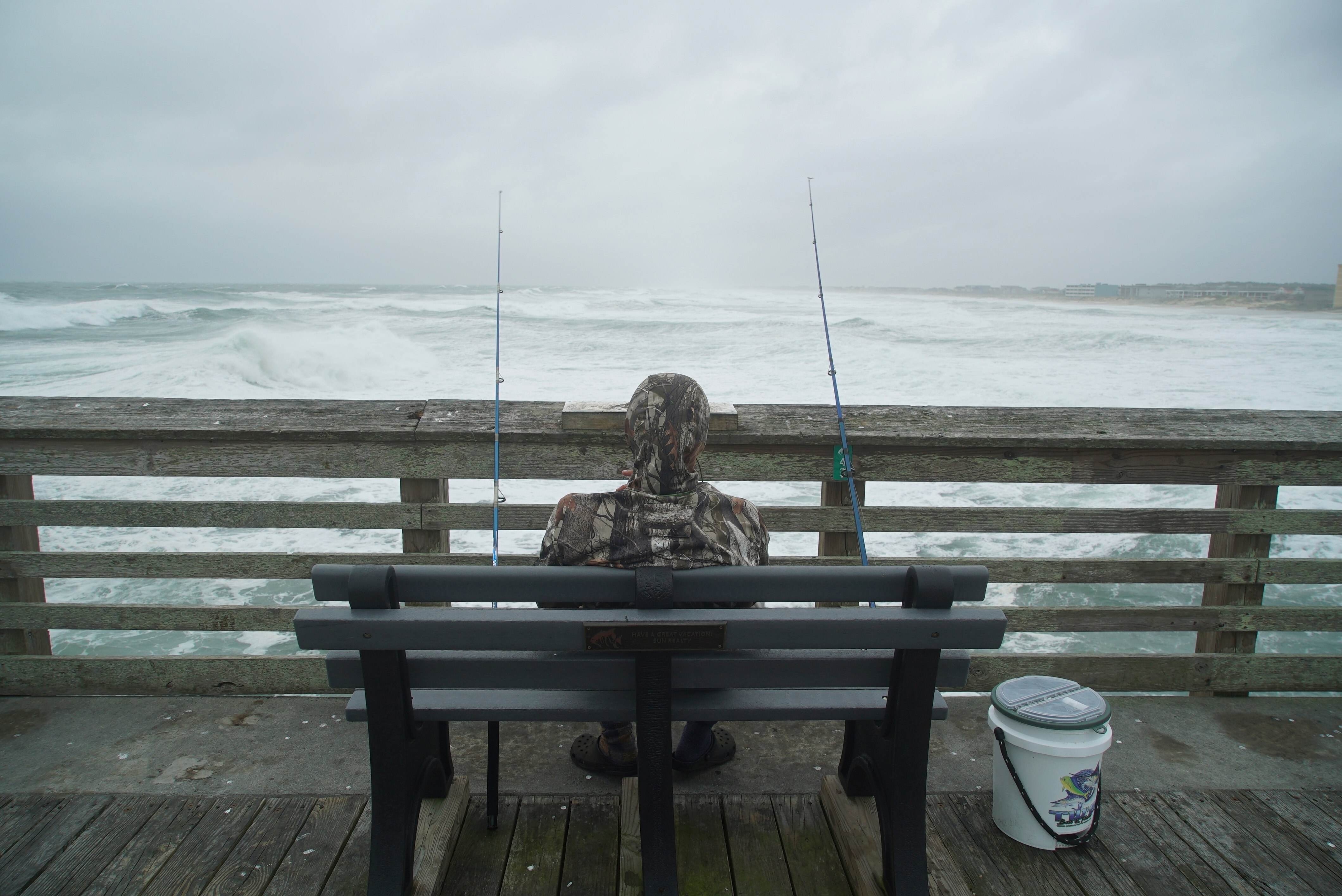 Sebastian Kettner fishes on Jennette's Pier as waves from Hurricane Erin crash ashore in Nags Head, N.C., Thursday, Aug. 21, 2025. (AP Photo/Allen G. Breed)