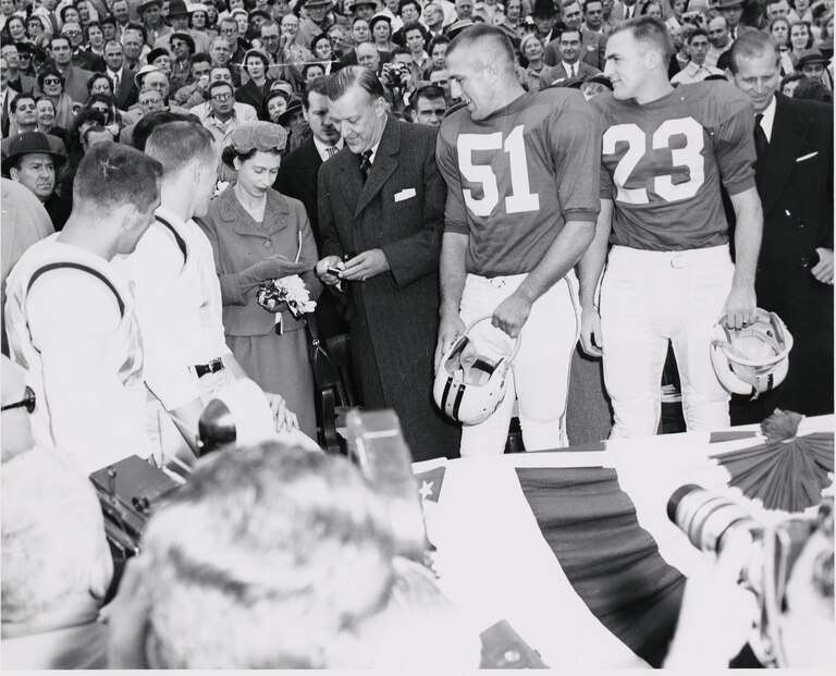 Queen Elizabeth II with Governor Theodore McKeldin and team captains while checking the coin to be used for the coin toss at a University of Maryland football game against the University of North Carolina, October 19, 1957. Prince Philip is pictured at the far right. Courtesy of University of Maryland Archives.