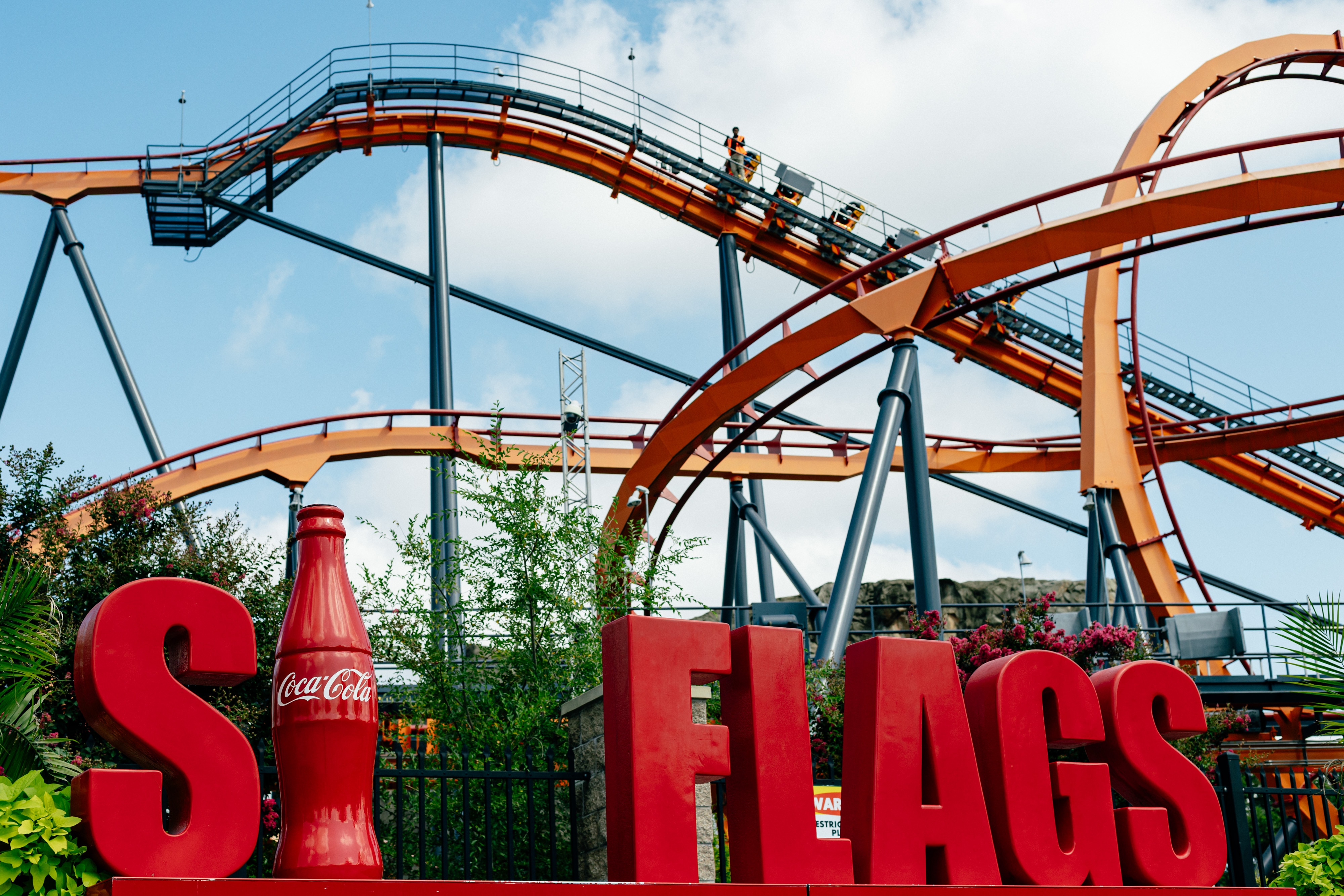 The Firebird rollercoaster can be seen beyond the Six Flags sign at Six Flags America in Bowie, MD on Saturday, Aug. 16, 2025. The amusement park will close permanently at the end of the 2025 season.