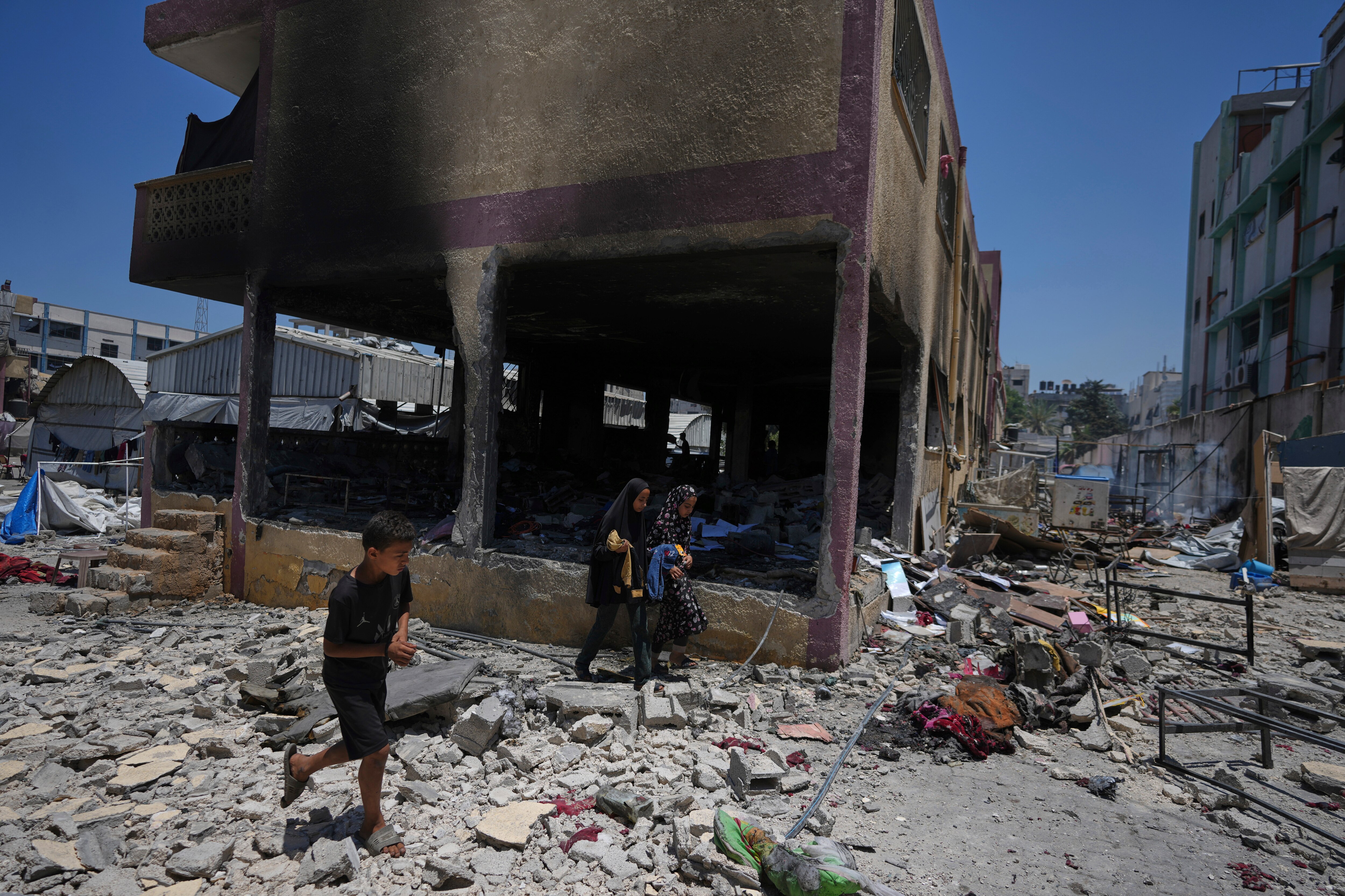 Palestinians survey the destruction at a school used as a shelter after it was struck by an Israeli airstrike in Gaza City, on Thursday, July 3, 2025.