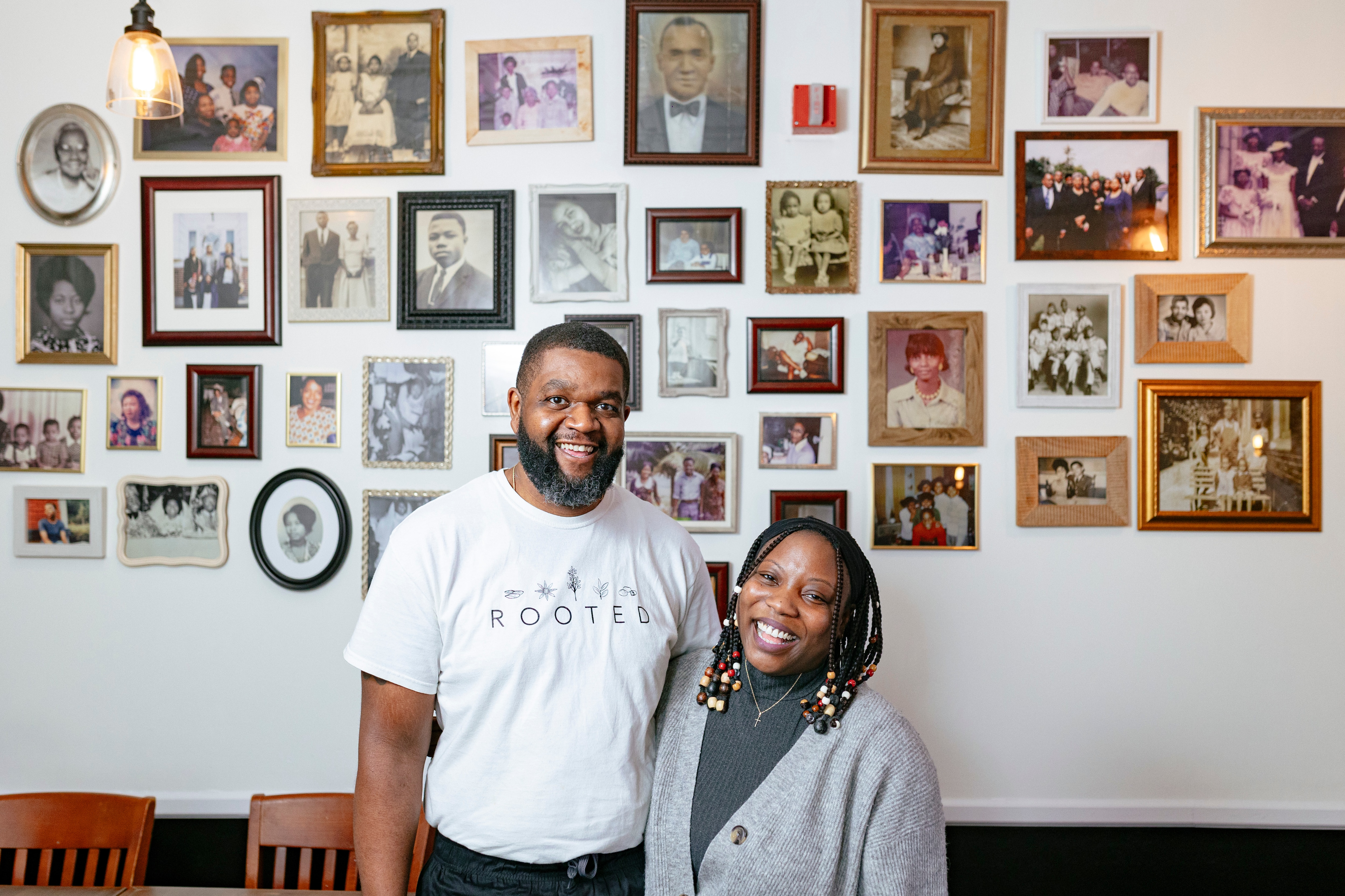 Owners Joe and Amanda Burton stand in front of a wall of family photos at Rooted Rotisserie. Their restaurant may soon feel the “Keith Lee effect.”