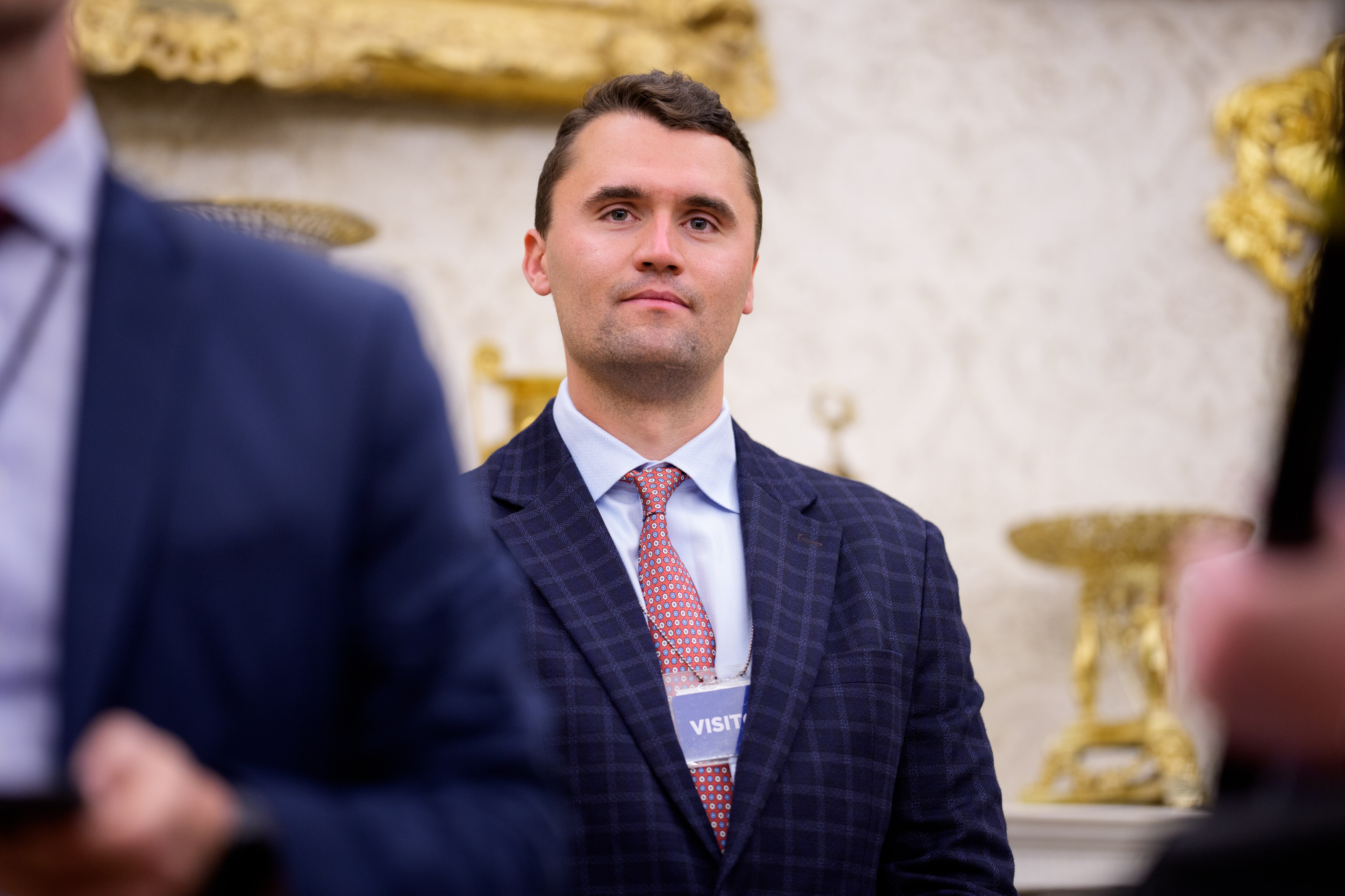 WASHINGTON, DC - MAY 28: Turning Point USA co-founder Charlie Kirk stands in the back of the room as U.S. President Donald Trump speaks during a swearing in ceremony for interim U.S. Attorney for Washington, D.C. Jeanine Pirro in the Oval Office of the White House on May 28, 2025 in Washington, DC. Trump has announced Pirro, a former Fox News personality, judge, prosecutor, and politician, after losing support in the Senate for his first choice, Ed Martin, over his views on the January 6, 2021 attack on the U.S. Capitol.