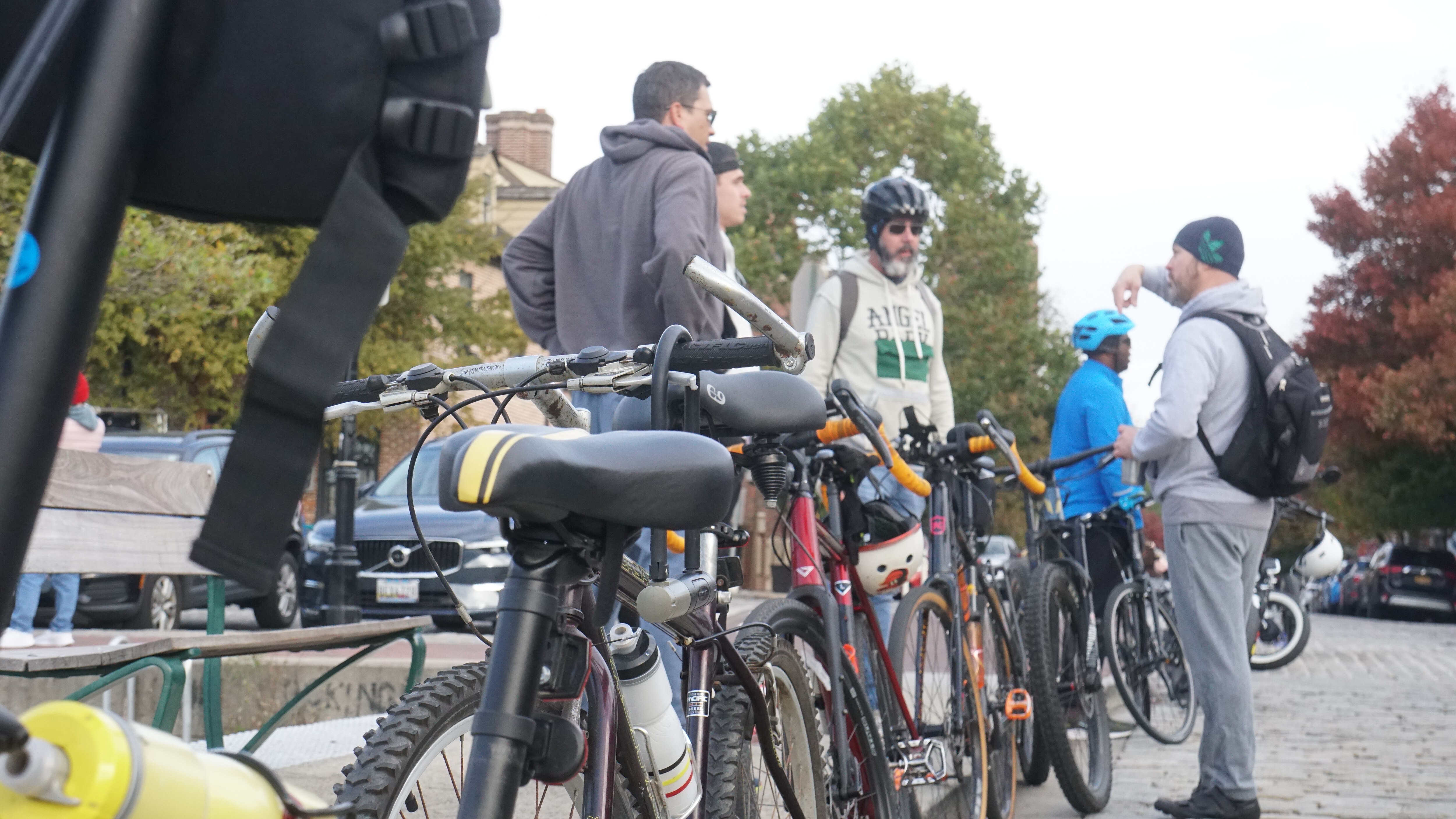 Five people stand outside next to a line of bicycles.