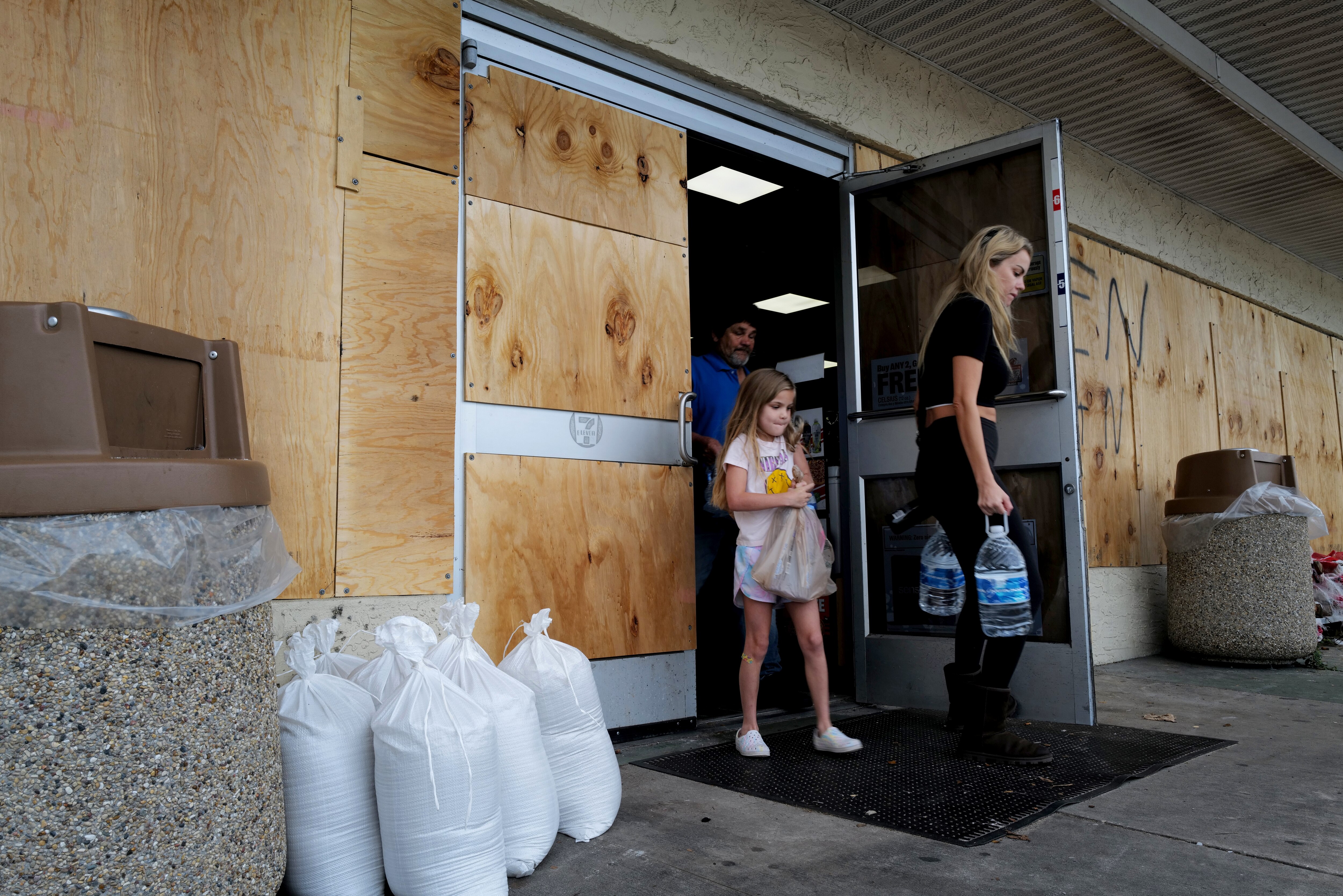 People stock up on supplies from a boarded-up store in St. Petersburg, Fla., as residents prepare for the arrival of Hurricane Milton.