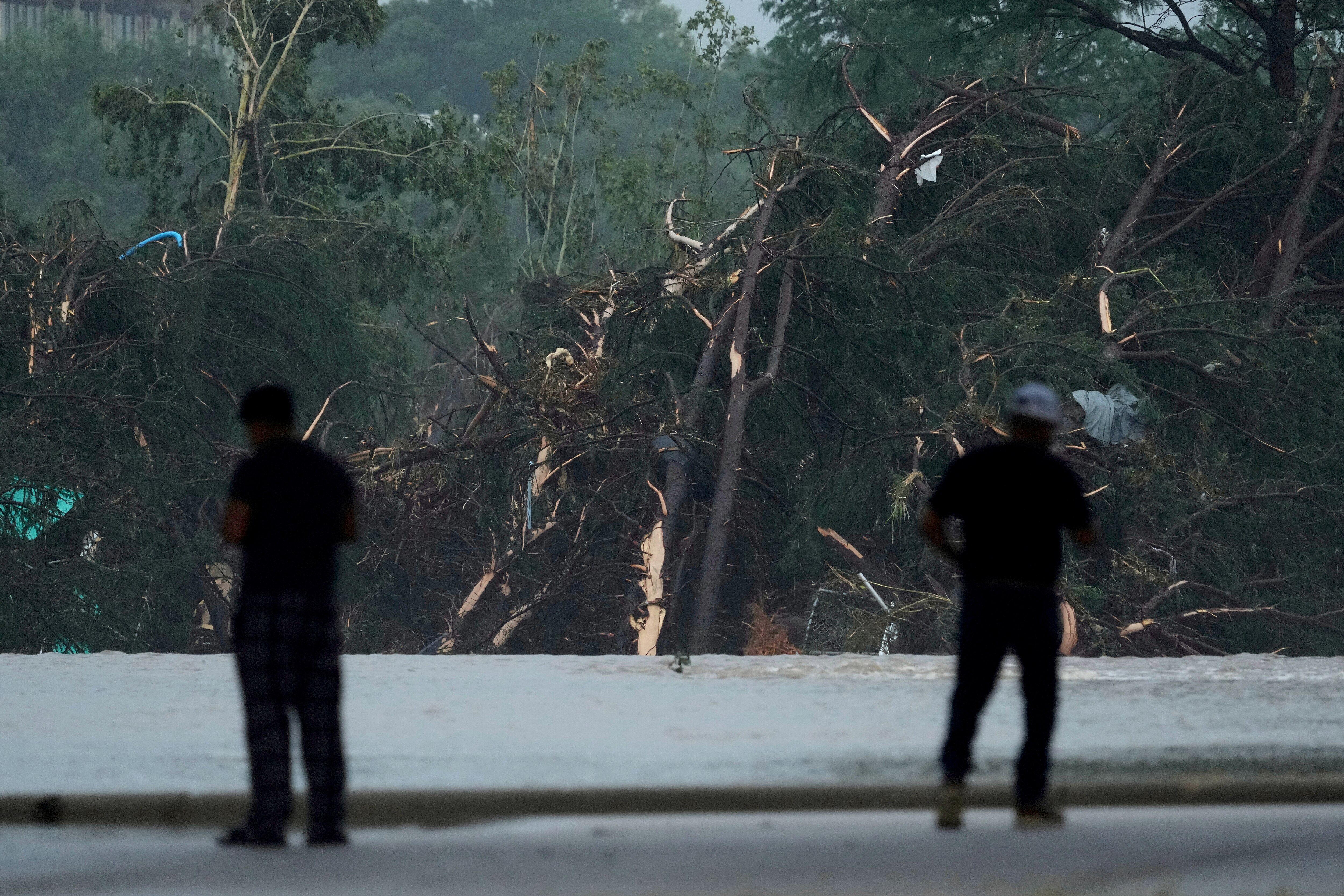 Onlookers survey damage caused along the Guadalupe River after a flash flood swept through the area, Friday, July 4, 2025, in Kerrville, Texas.