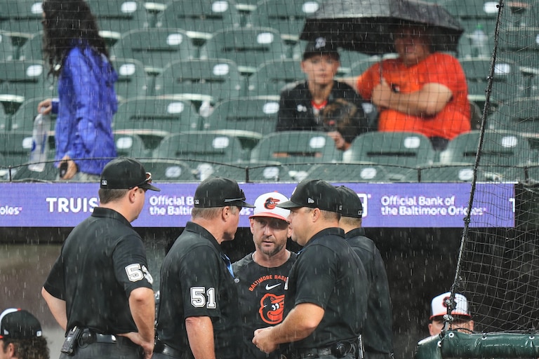 Baltimore Orioles manager Craig Albernaz, third from left, talks with umpires as Sunday's game against the Philadelphia Phillies is delayed for the second time due to rain.