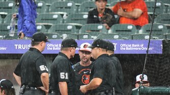 Baltimore Orioles manager Craig Albernaz, third from left, talks with umpires as Sunday's game against the Philadelphia Phillies is delayed for the second time due to rain.