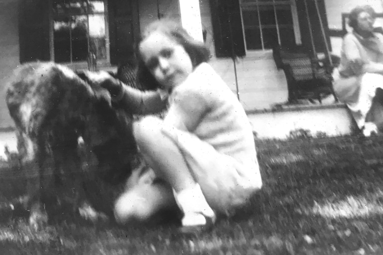 Kitty Washburne, when she was four years-old, petting a dog.