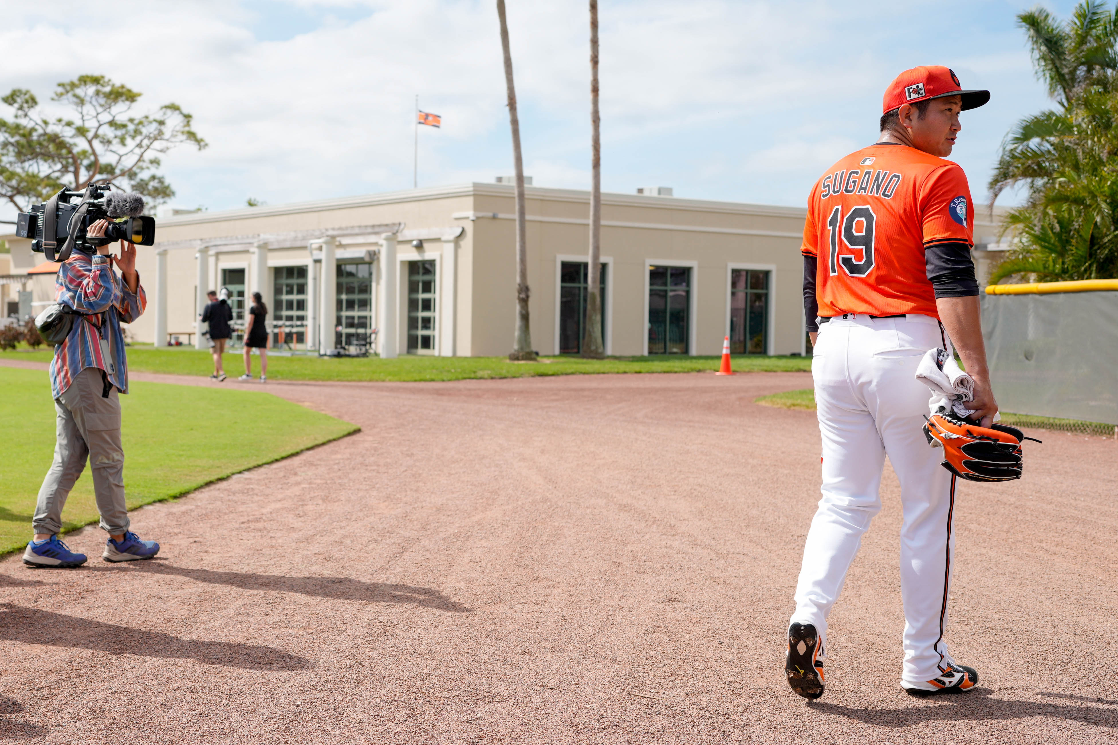 Journalists with several Japanese news outlets document newly signed Baltimore Orioles pitcher Tomoyuki Sugano, right, as he warms up with the team during spring training.