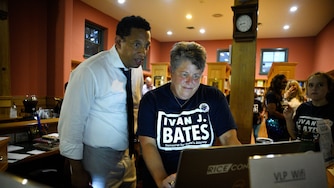 Baltimore City State's Attorney candidate Ivan Bates (left) and Rachael Rice (right) watch results come in at Bates' election night event. Maryland held its primary election on Tuesday, July 19.