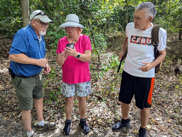 Water access advocate Mike Lofton helps Liudmila and Sergey Pakharenko find Beverly Triton Nature Area on the map while hiking South River Farm Park. They were looking for a beach.
