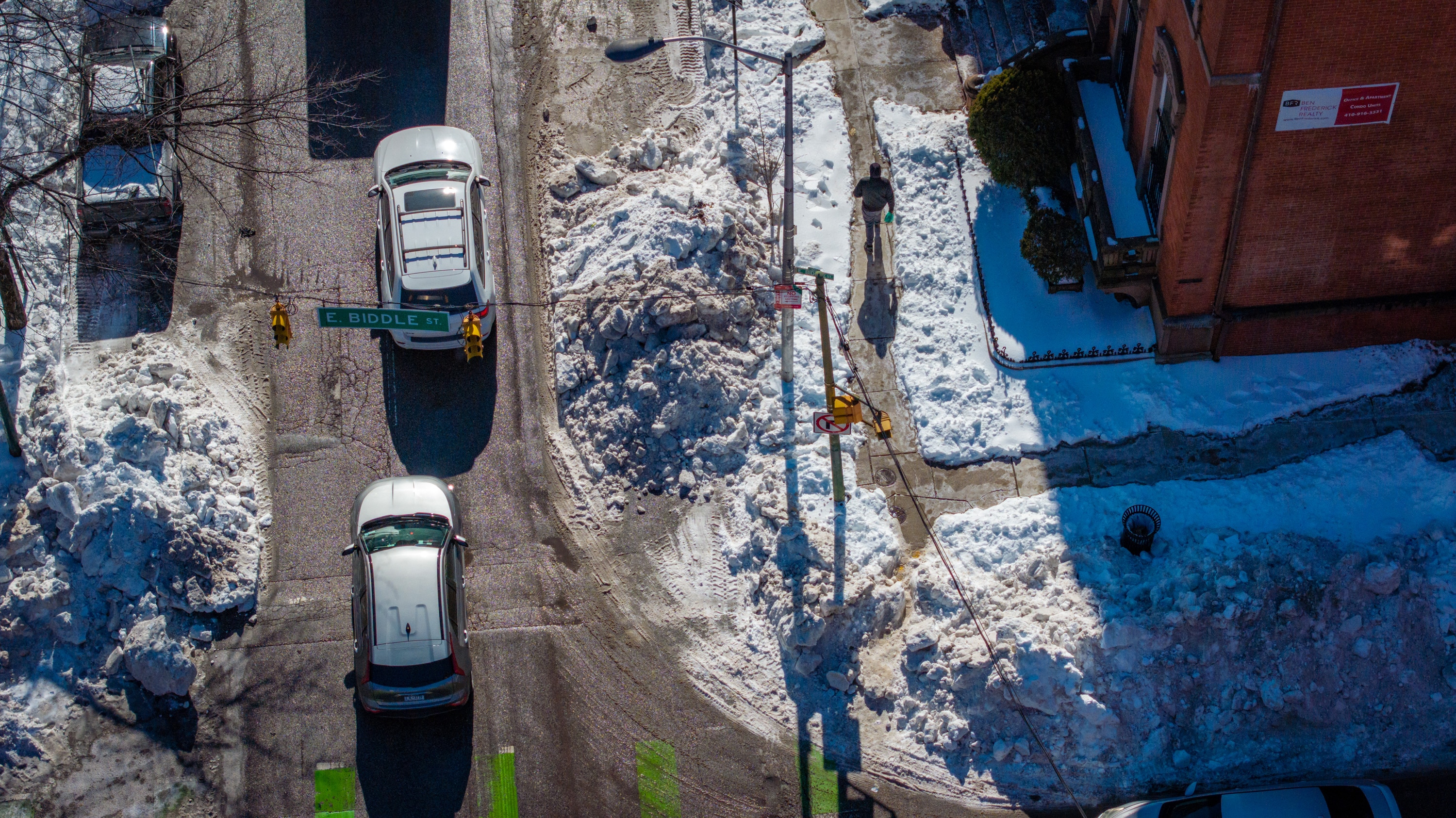A pedestrian walks on the plowed sidewalk at St. Paul and East Biddle streets as vehicle traffic is constrained to one lane last week.