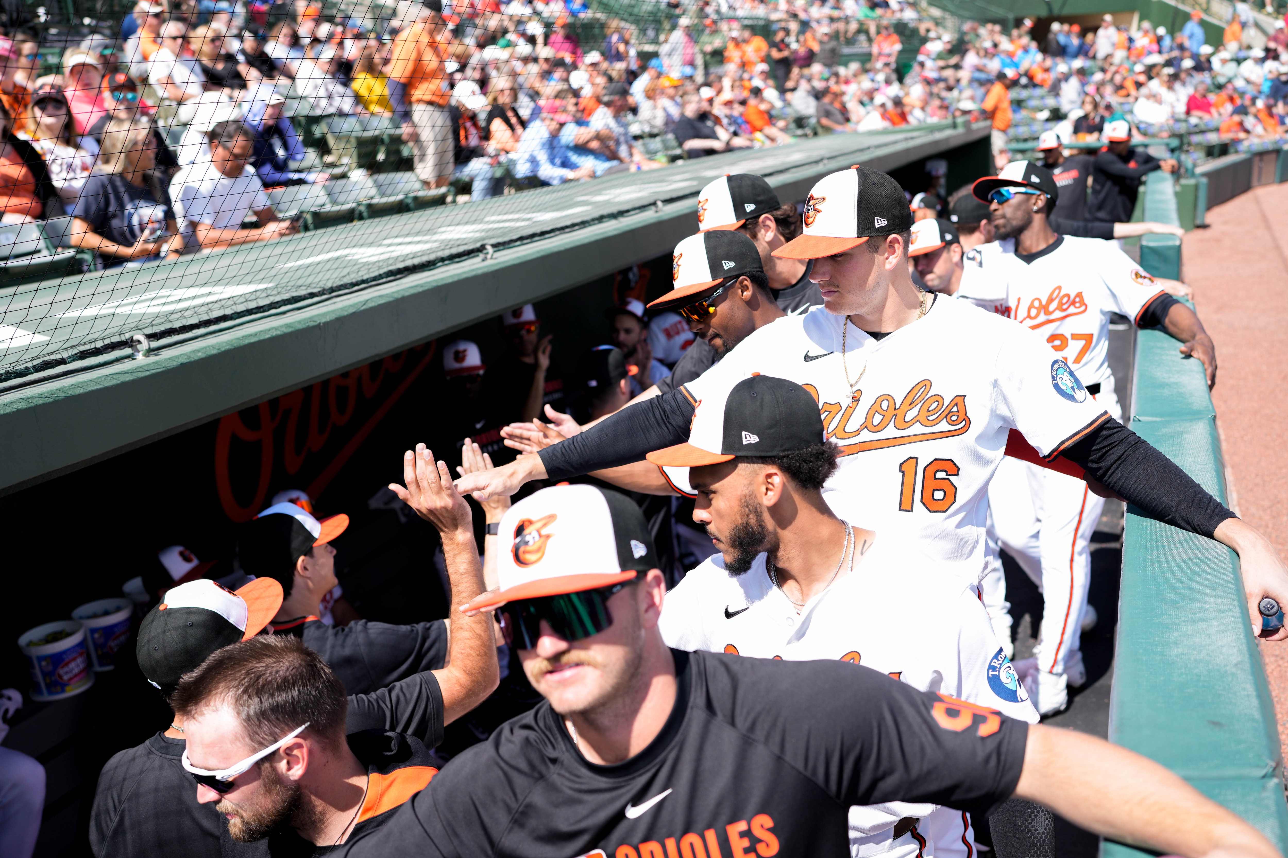 Orioles third baseman Coby Mayo high-fives teammates as they enter the dugout ahead of a Grapefruit League game.