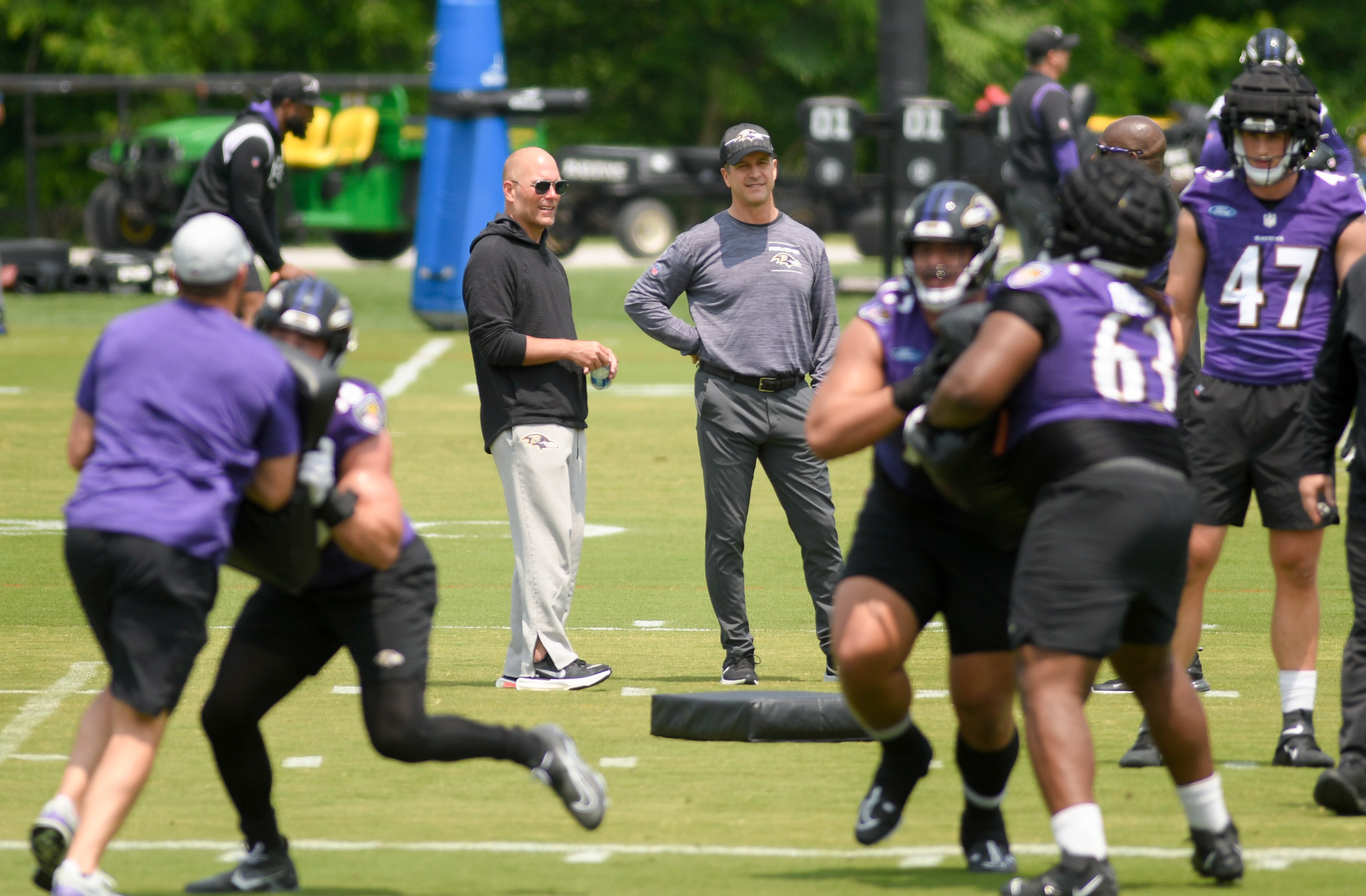 Baltimore Ravens General Manager Eric DeCosta, left, and coach John Harbaugh watch organized team activities in May in Owings Mills.