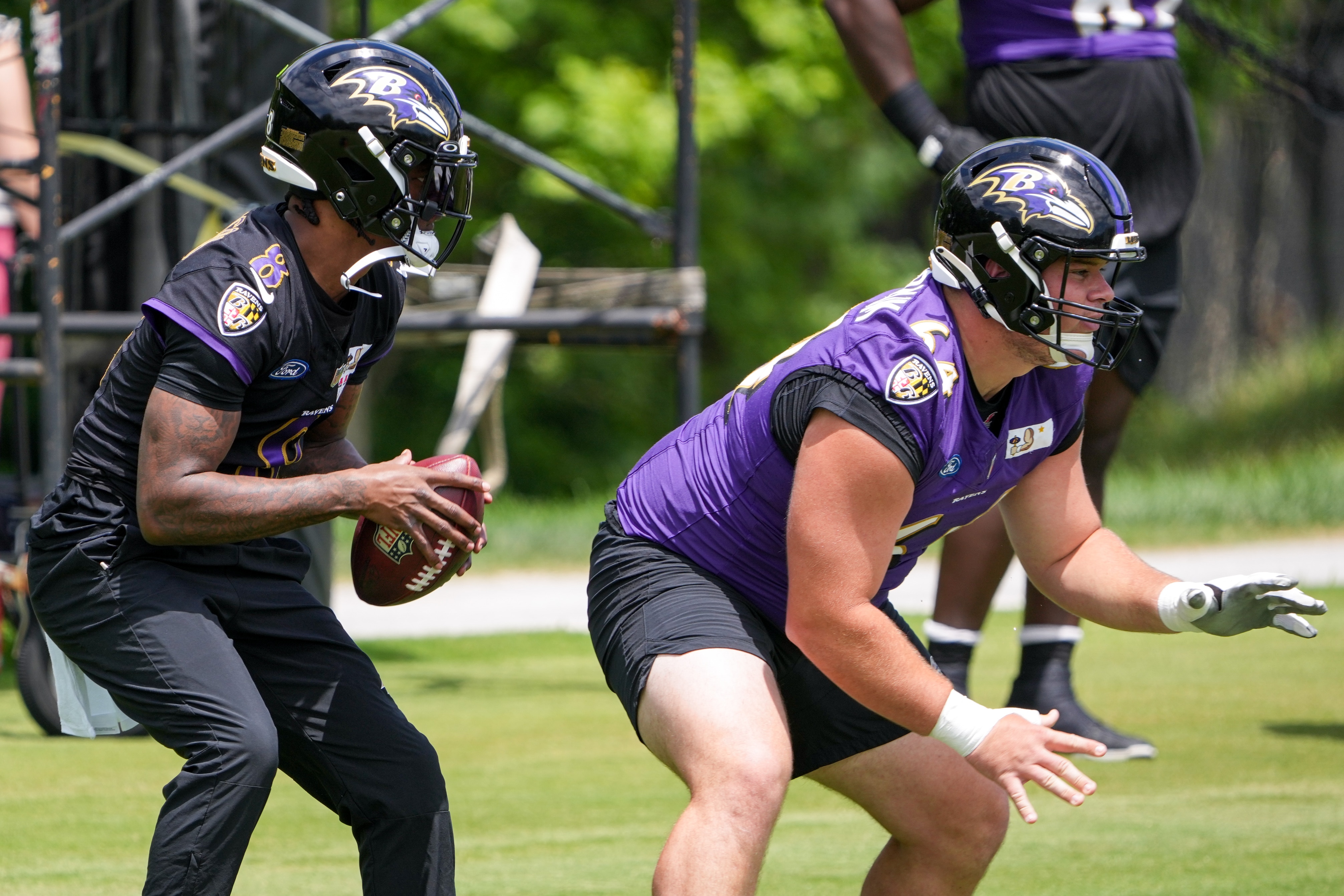Center Tyler Linderbaum (64) hikes the ball to quarterback Lamar Jackson (8) during the Baltimore Ravens’ first mandatory minicamp of the year at the Under Armour Performance Center in Owings Mills on June 11, 2024.