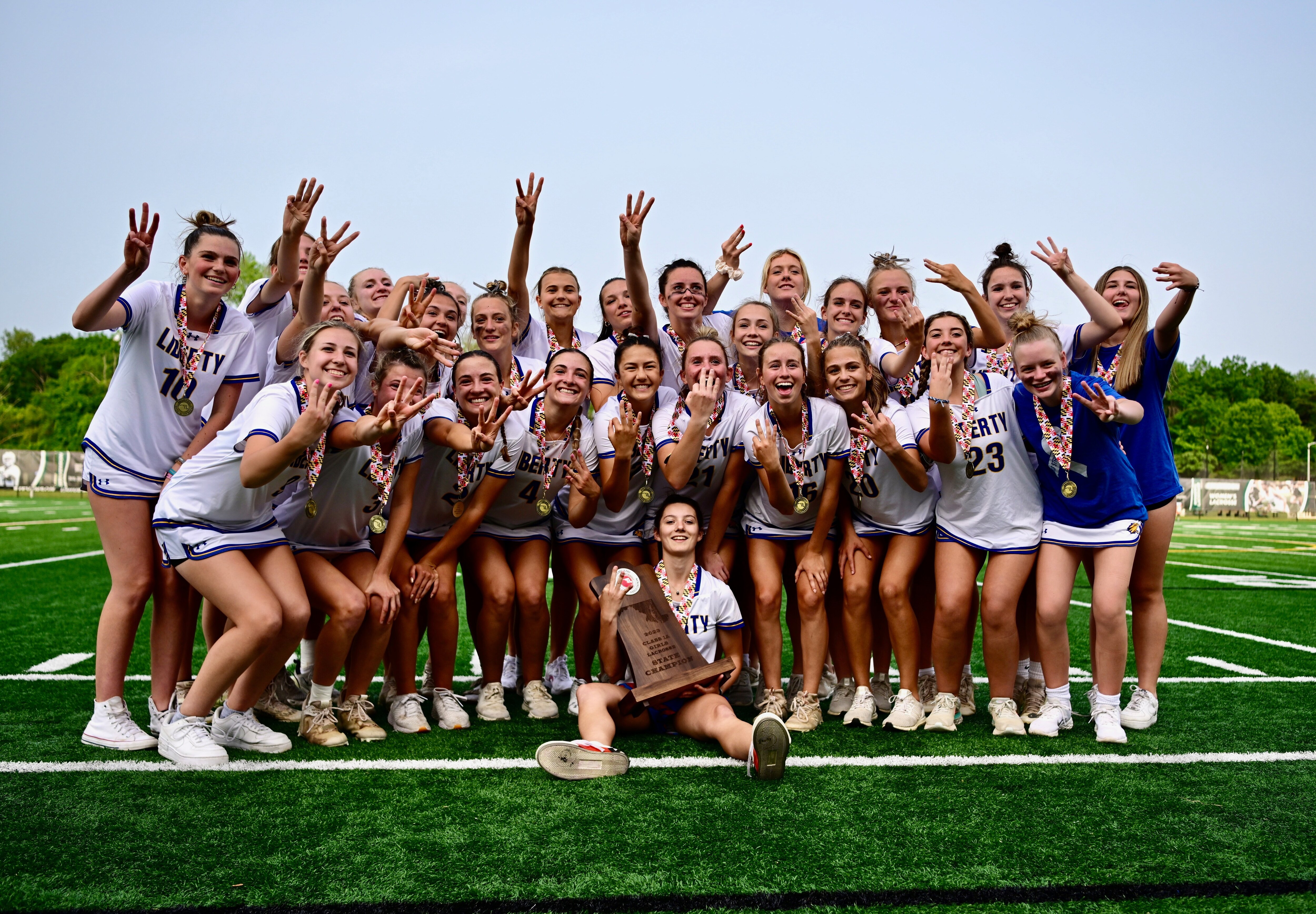 In a team pose, members of the Liberty girls lacrosse team each flash three fingers to symbolize their third consecutive Class 1 state championship, following their 14-10 win over Fallston, Tuesday night at Stevenson University