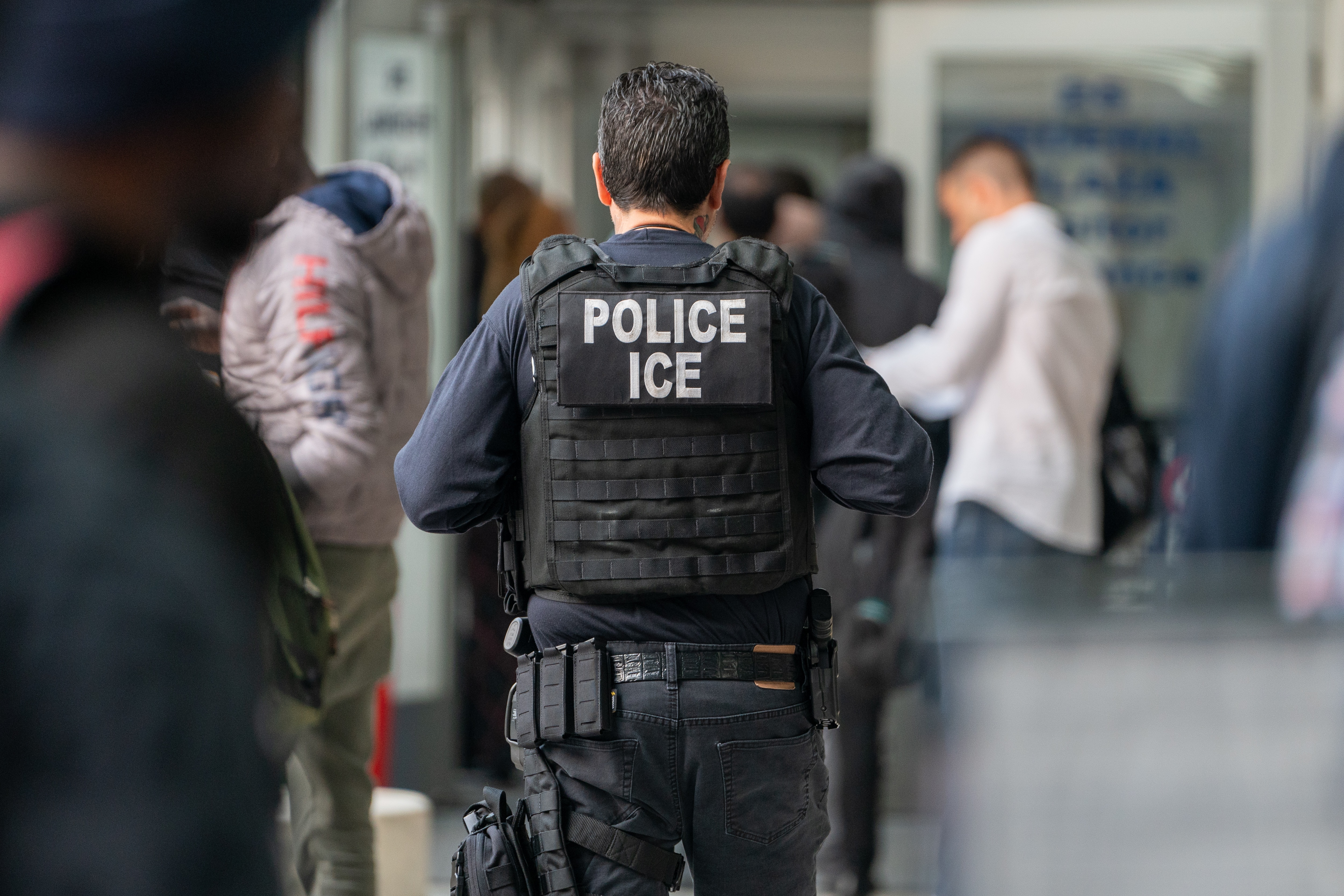NEW YORK, NEW YORK - JUNE 6: An ICE agent monitors hundreds of asylum seekers being processed upon entering the Jacob K. Javits Federal Building on June 6, 2023 in New York City.