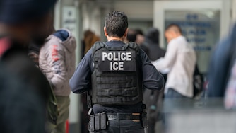 NEW YORK, NEW YORK - JUNE 6: An ICE agent monitors hundreds of asylum seekers being processed upon entering the Jacob K. Javits Federal Building on June 6, 2023 in New York City.