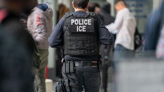 NEW YORK, NEW YORK - JUNE 6: An ICE agent monitors hundreds of asylum seekers being processed upon entering the Jacob K. Javits Federal Building on June 6, 2023 in New York City.